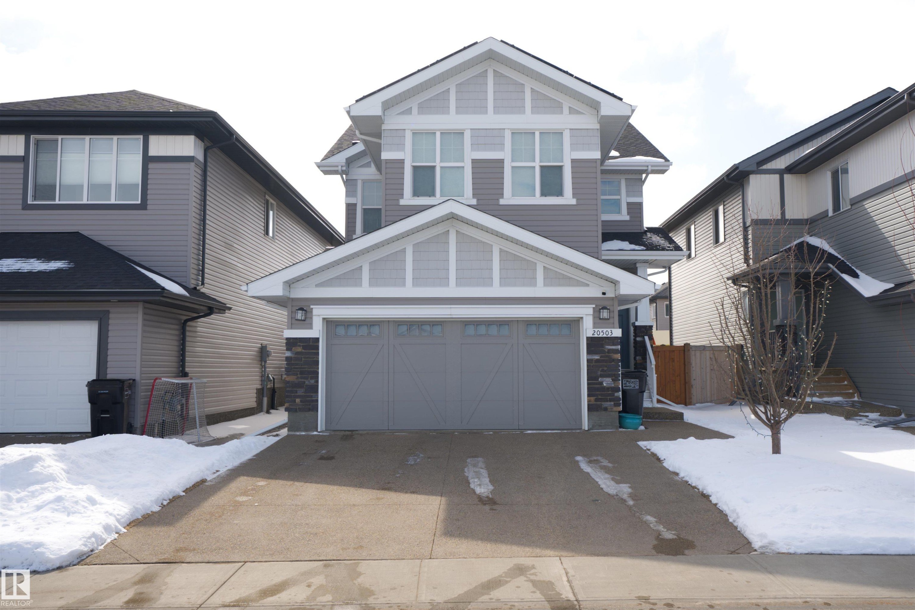 The property features a two-story exterior with grey siding and white trim, complemented by a two-car garage with an overhead door - 20503 99 Avenue, Edmonton, AB - Outdoor With Facade