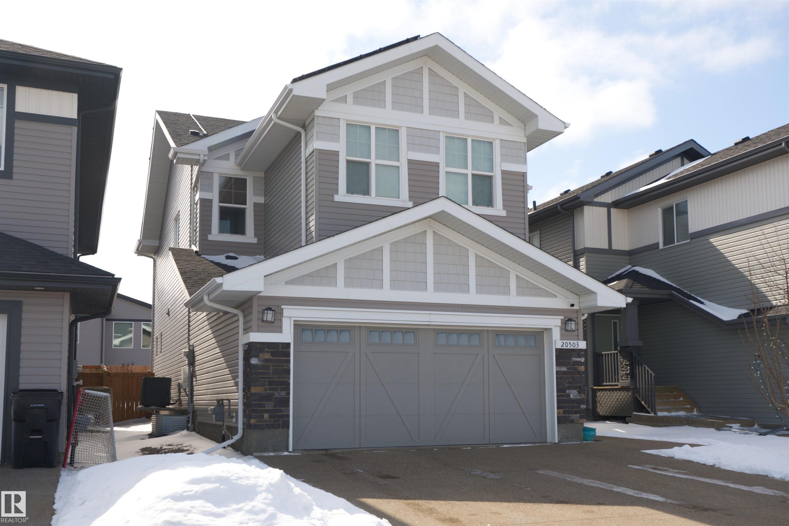 The property features a two-story exterior with grey siding and white trim, including decorative gables - 20503 99 Avenue, Edmonton, AB - Outdoor With Facade