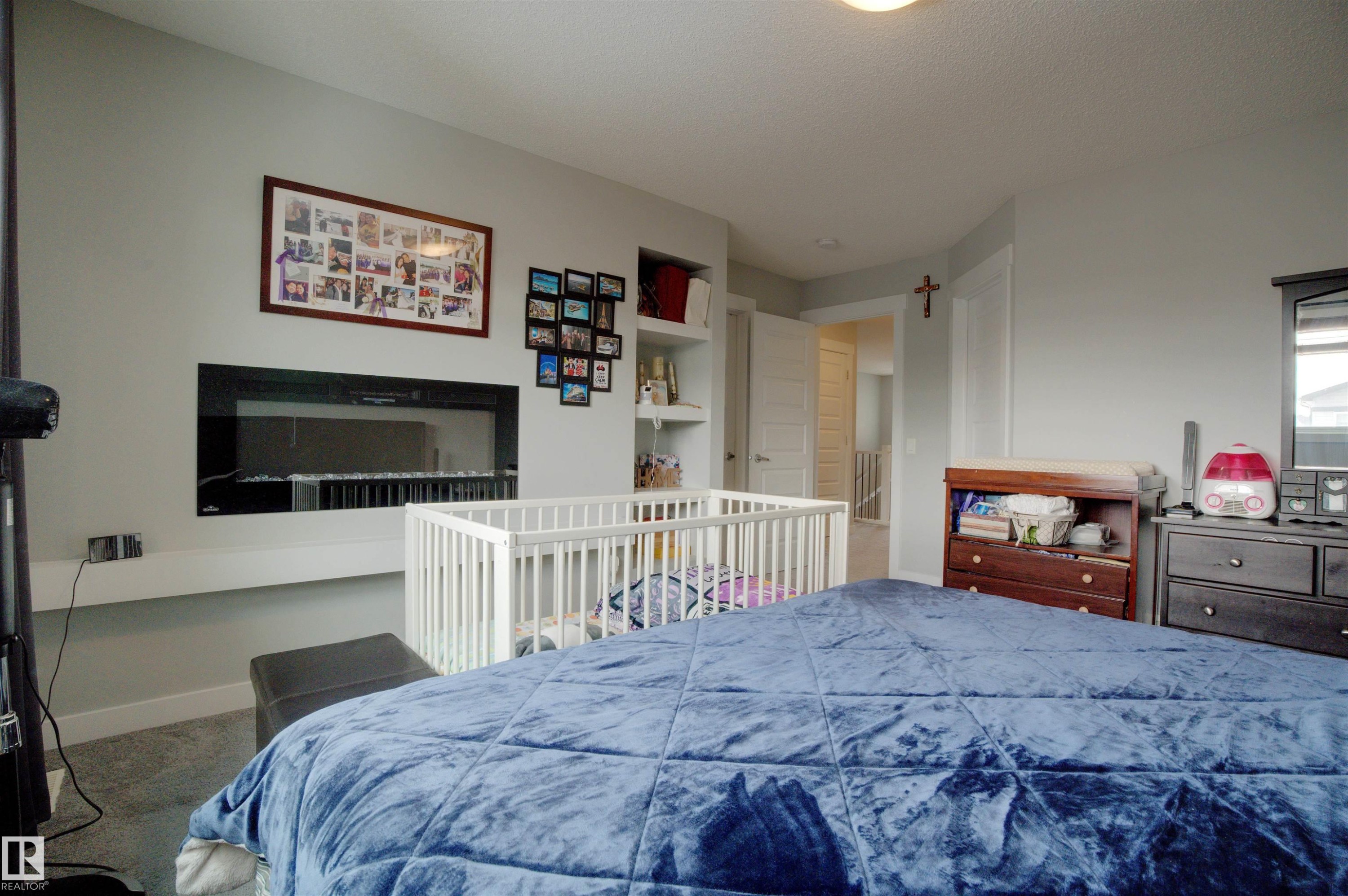 Bedroom featuring a built-in electric fireplace and shelving, with carpeted flooring - 20503 99 Avenue, Edmonton, AB - Indoor Photo Showing Bedroom