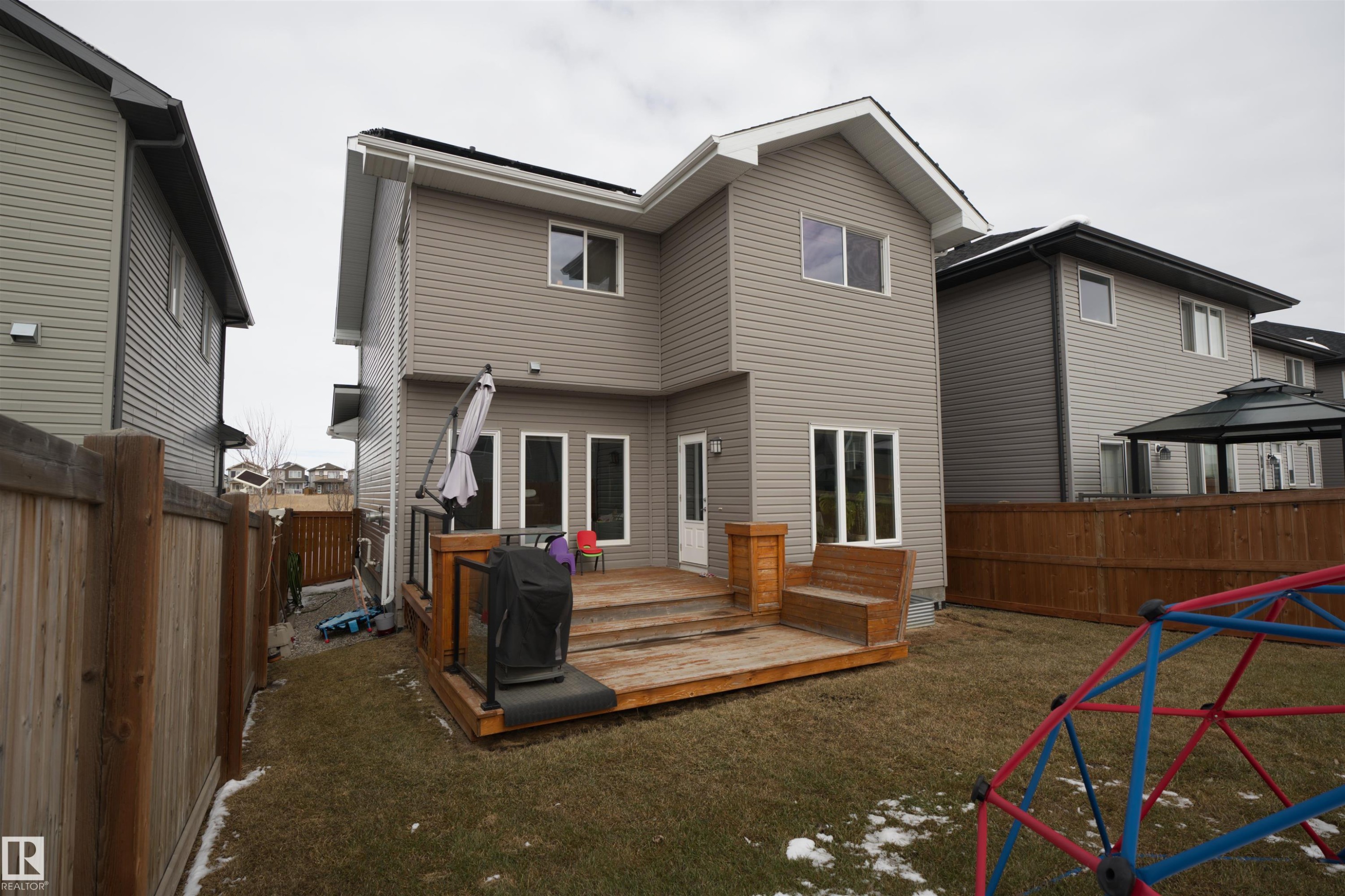 The property features a spacious rear yard with a wooden deck, a built-in wooden bench, and a privacy fence - 20503 99 Avenue, Edmonton, AB - Outdoor With Exterior