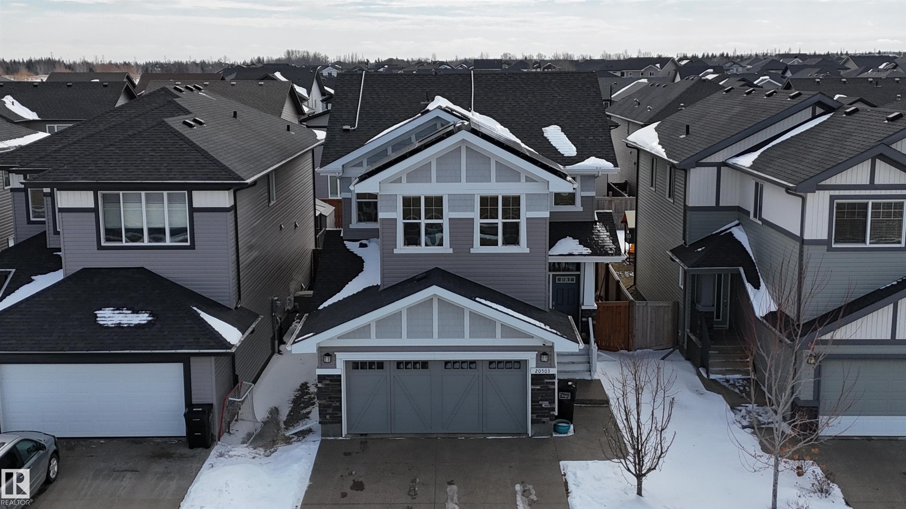 Well-maintained property featuring a gray exterior with white trim, a dark gray roof, and an attached garage with a dark gray door - 20503 99 Avenue, Edmonton, AB - Outdoor With Facade