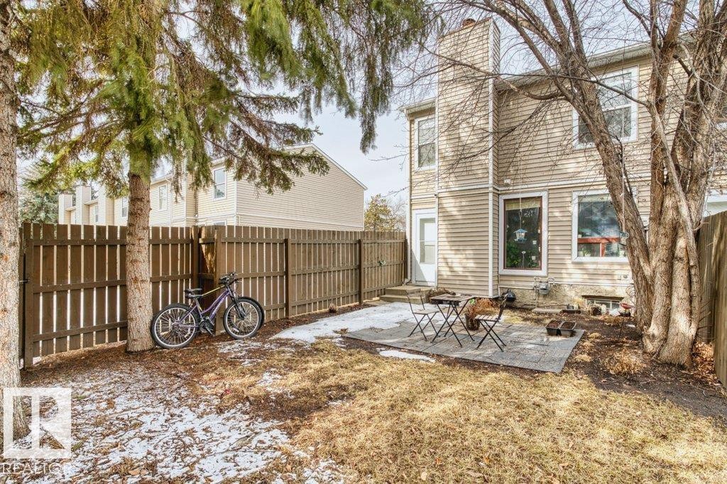 The property features a private yard with a paved patio area, a wooden fence, and mature trees - 638 Saddleback Road, Edmonton, AB - Outdoor