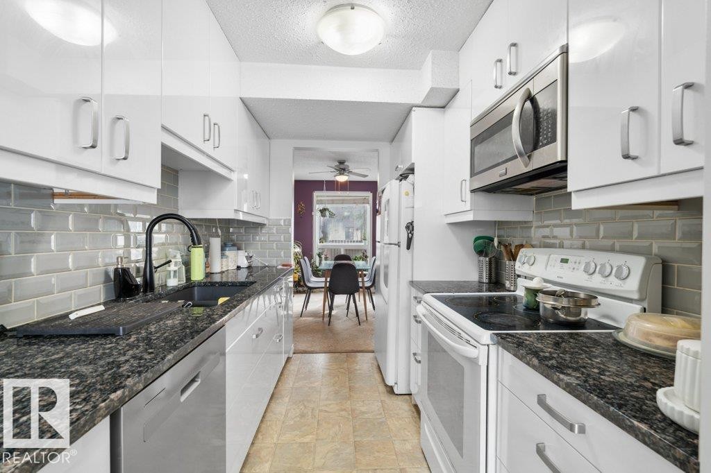 Bright kitchen with white cabinetry, dark granite countertops, and a subway tile backsplash - 638 Saddleback Road, Edmonton, AB - Indoor Photo Showing Kitchen