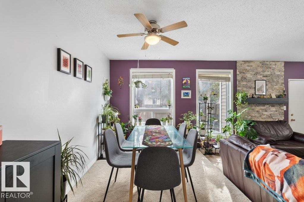 Dining area featuring a ceiling fan with light fixture, large windows providing natural light, and a brick accent wall - 638 Saddleback Road, Edmonton, AB - Indoor Photo Showing Dining Room