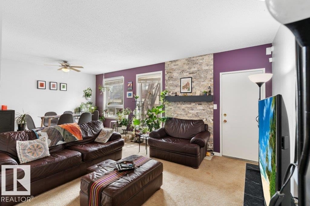 Living area featuring neutral carpeting, a decorative stone accent wall, and a ceiling fan - 638 Saddleback Road, Edmonton, AB - Indoor Photo Showing Living Room