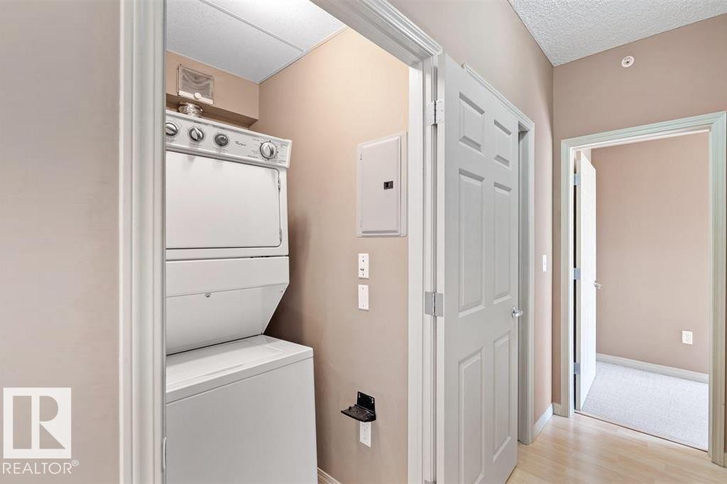 Dedicated laundry area featuring a white stacked washer and dryer unit - 1-204 4245 139 Avenue, Edmonton, AB - Indoor Photo Showing Laundry Room