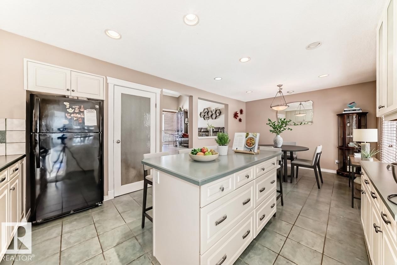 The kitchen features a functional island with drawers, ample cabinetry, recessed lighting, and tile flooring - 597 Millbourne Road E, Edmonton, AB - Indoor Photo Showing Kitchen With Upgraded Kitchen