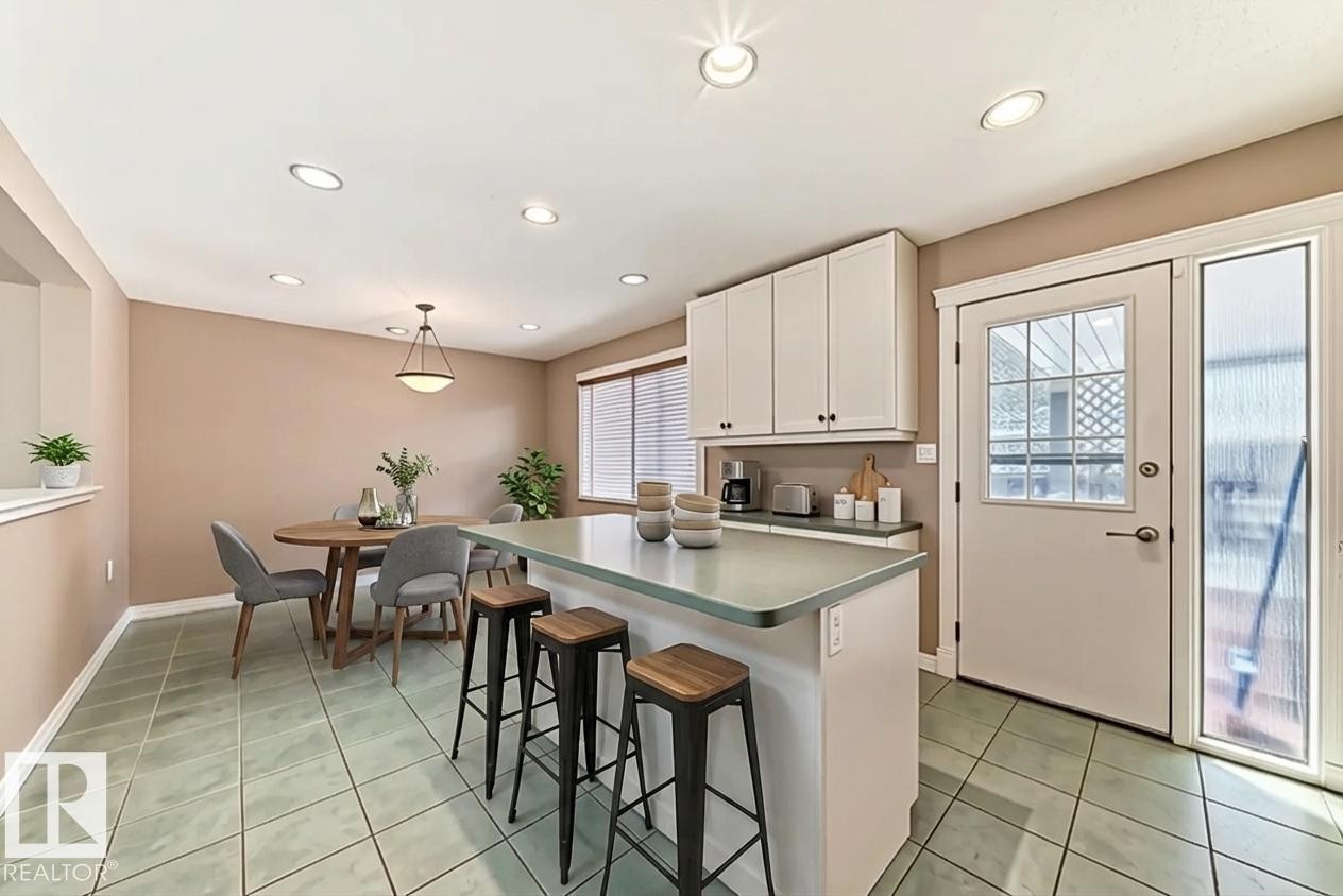 The kitchen and dining area feature light green tiled flooring and recessed lighting - 597 Millbourne Road E, Edmonton, AB - Indoor