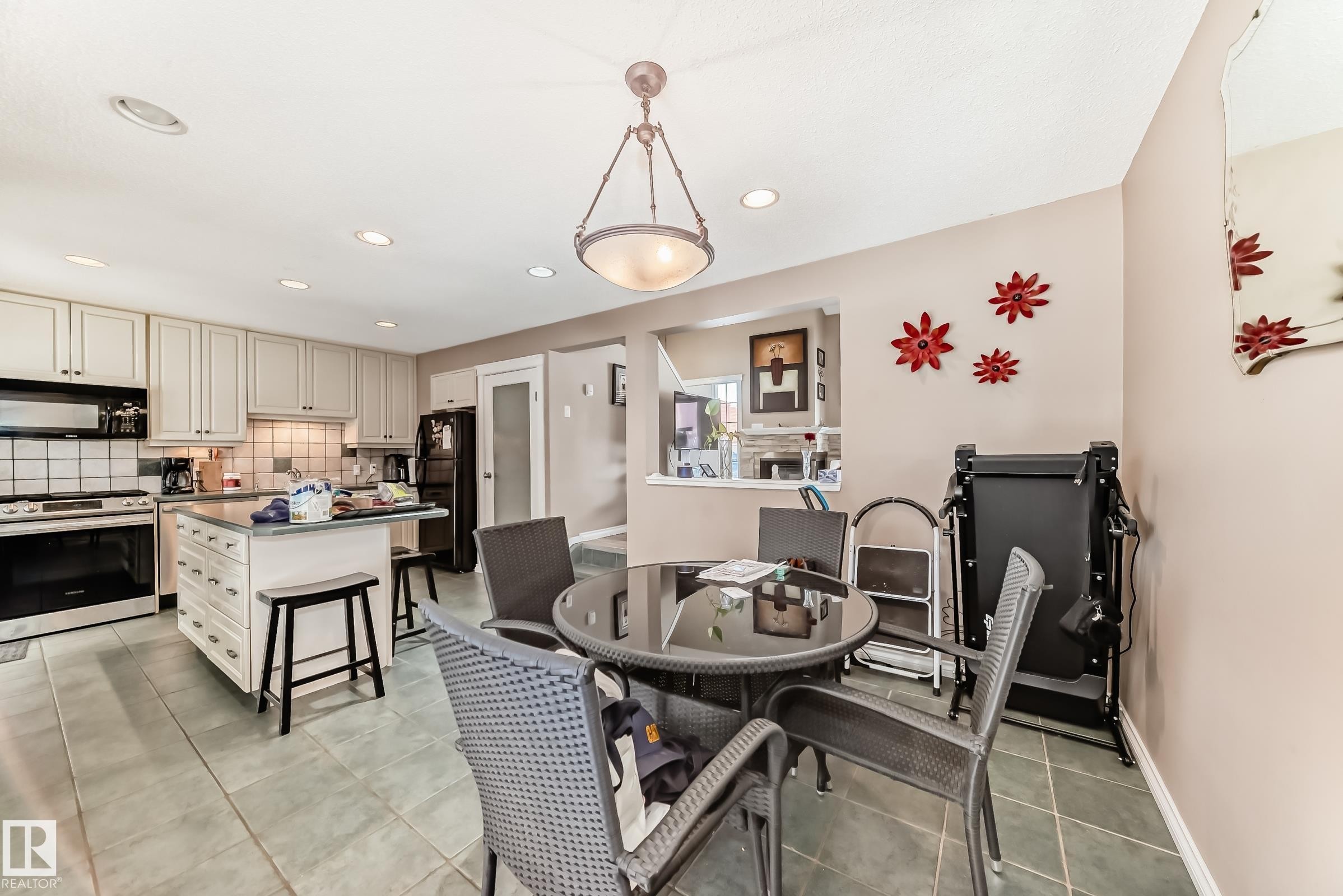 The kitchen features light-colored cabinetry, a center island with a countertop, and stainless steel appliances including an oven and range hood - 597 Millbourne Road E, Edmonton, AB - Indoor