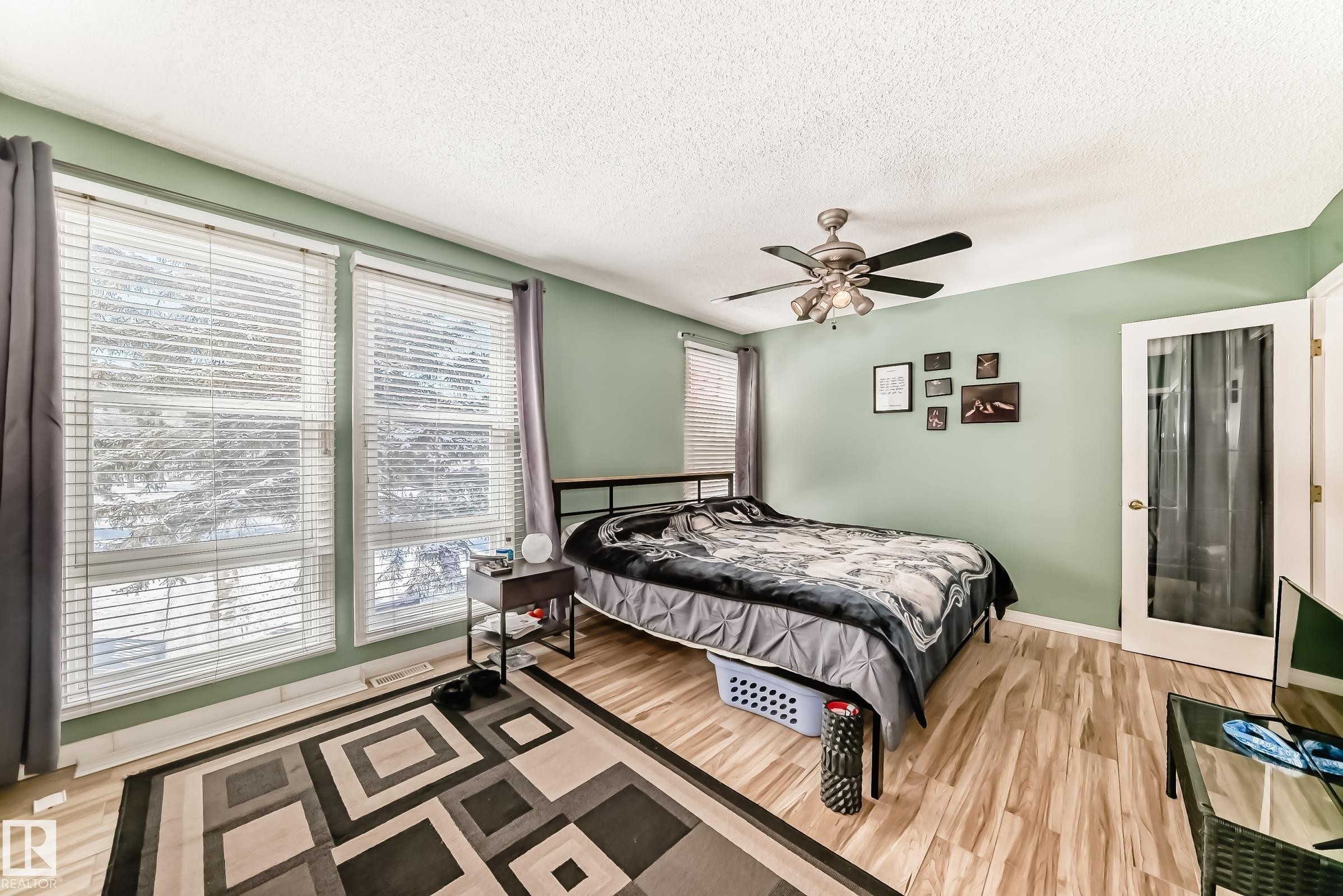 This room features light green walls, light wood-style flooring, and a ceiling fan - 597 Millbourne Road E, Edmonton, AB - Indoor Photo Showing Bedroom