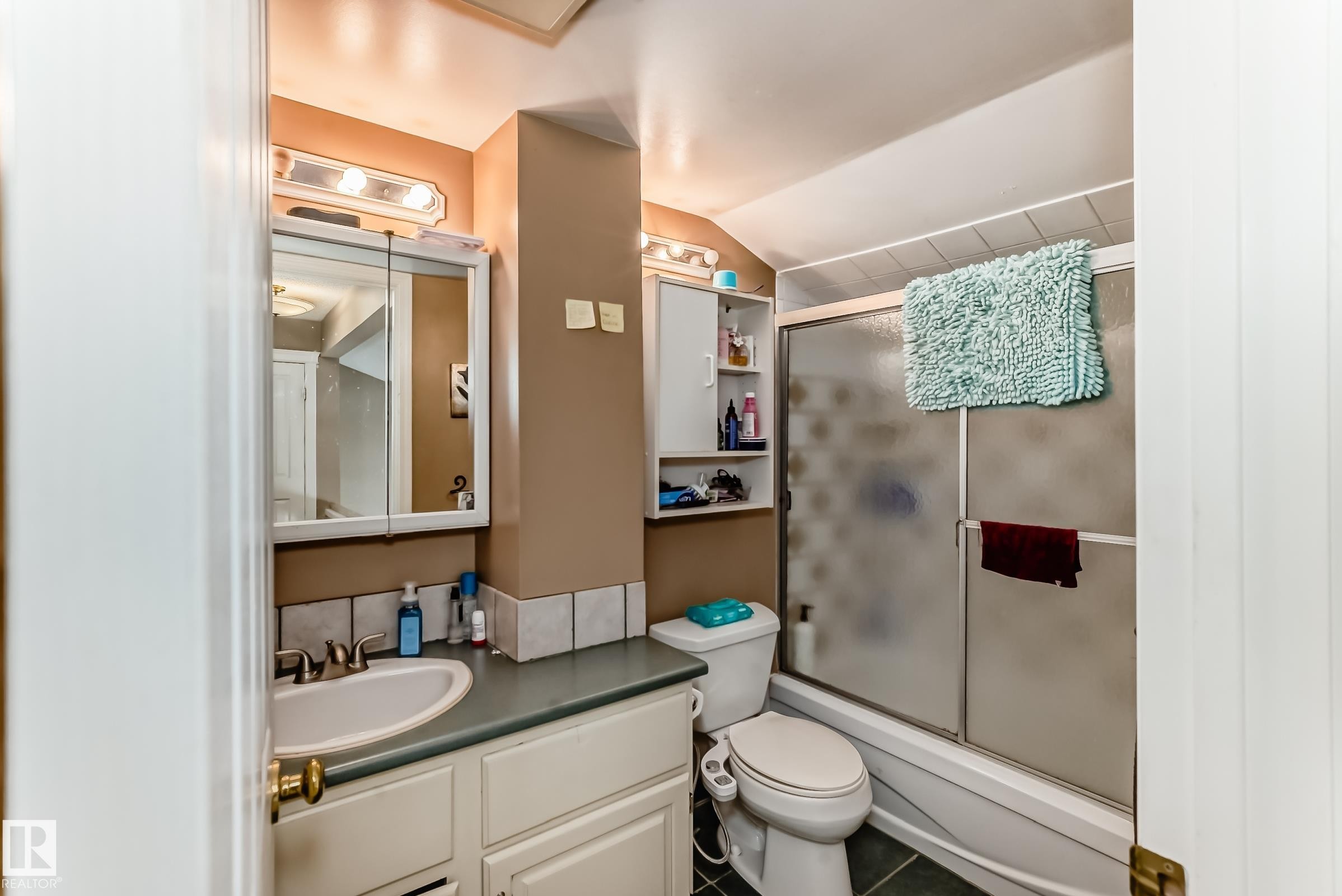 Bathroom featuring a vanity with an integrated sink, a medicine cabinet with a mirrored front, and a shower-bathtub combination with a sliding glass door - 597 Millbourne Road E, Edmonton, AB - Indoor Photo Showing Bathroom