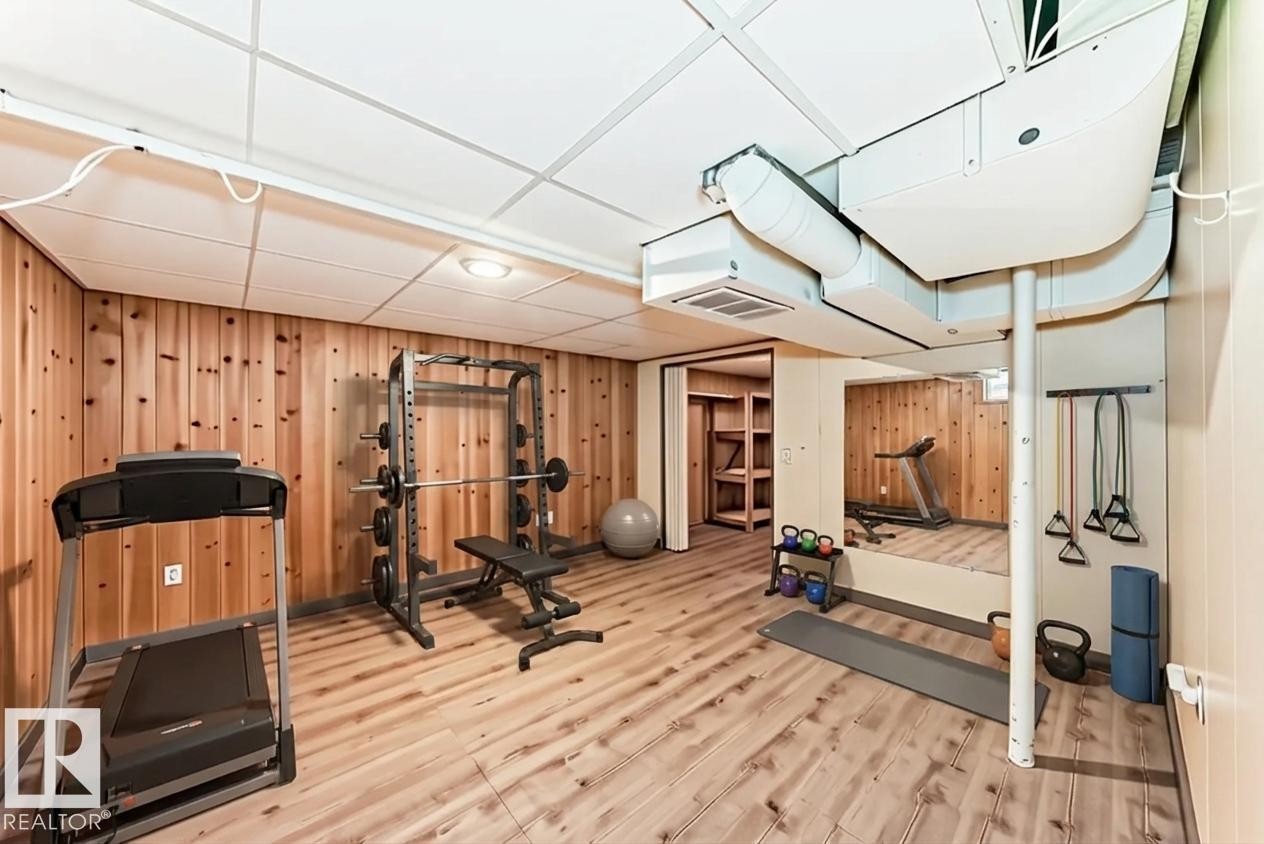 This versatile space features wood paneled walls, light wood-style flooring, and a drop ceiling with recessed lighting - 597 Millbourne Road E, Edmonton, AB - Indoor Photo Showing Gym Room