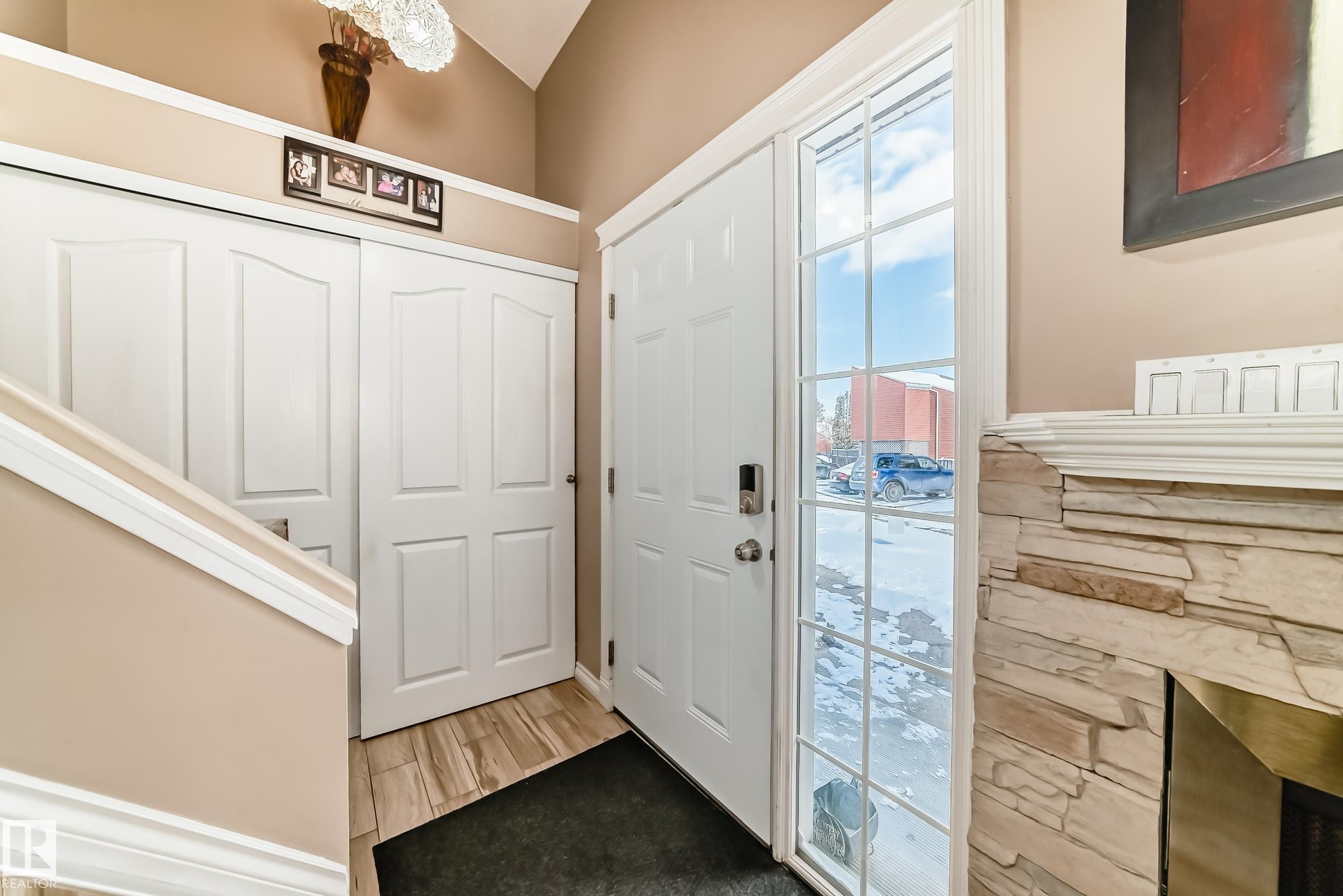 Entryway featuring a white front door with a full-length window, wood-look flooring, and a stone-clad fireplace with a mantel - 597 Millbourne Road E, Edmonton, AB - Indoor Photo Showing Other Room