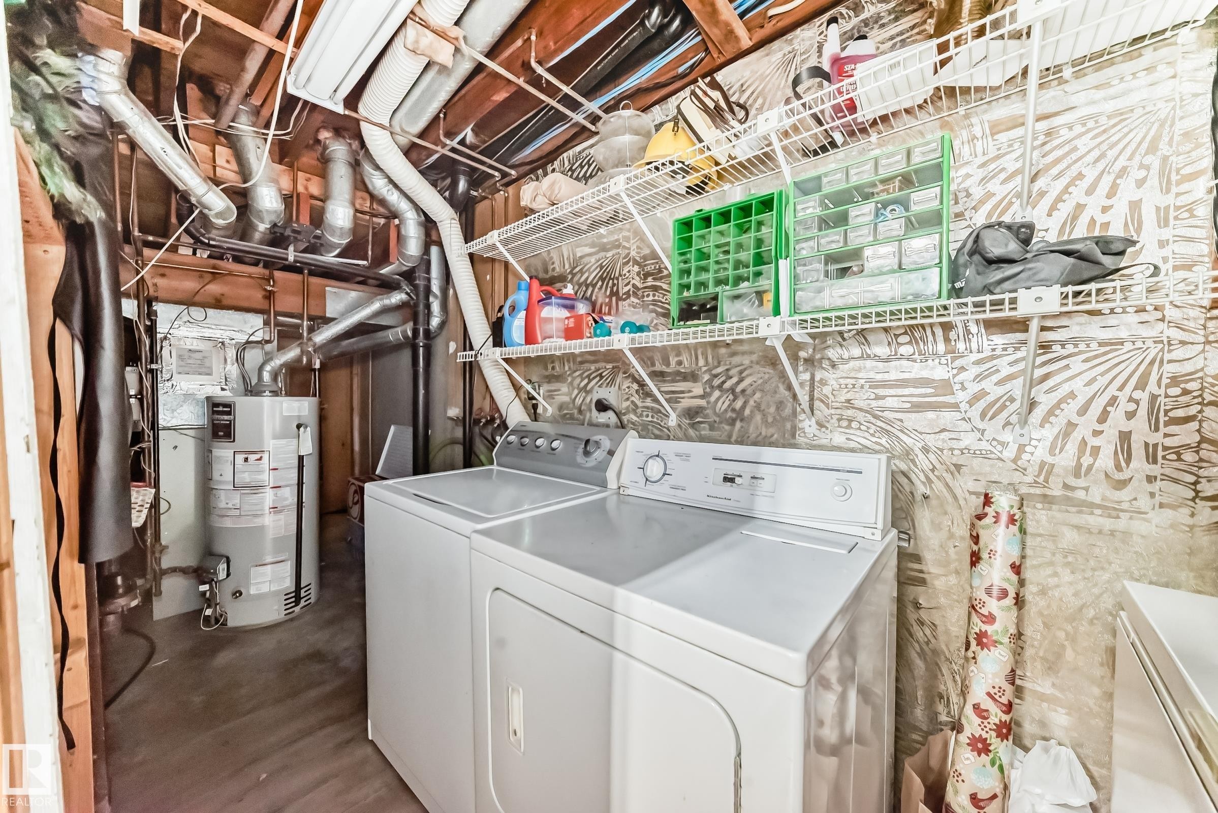 Utility area featuring a washer and dryer, a water heater, and overhead shelving for storage - 597 Millbourne Road E, Edmonton, AB - Indoor Photo Showing Laundry Room