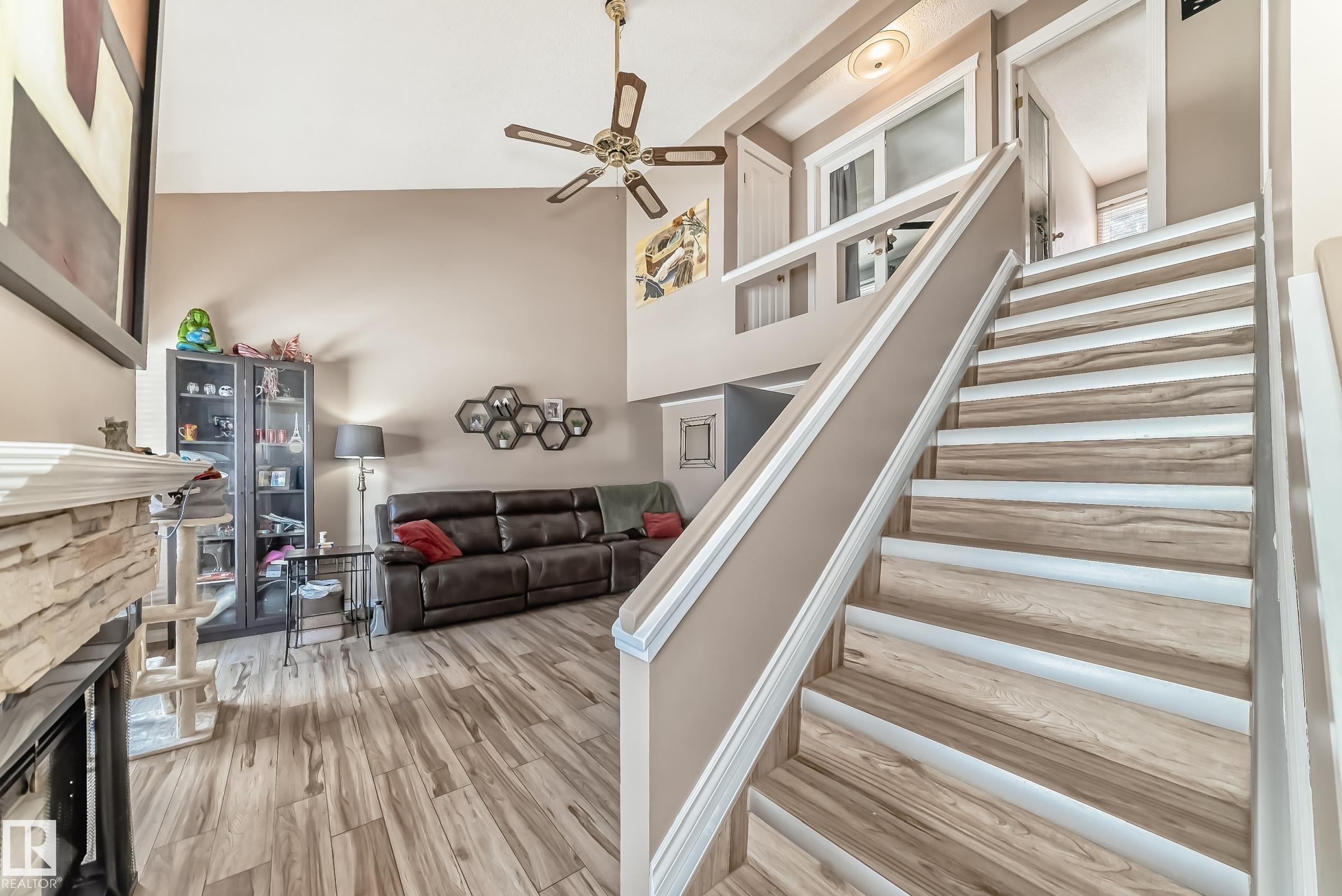 The living area features high ceilings, a ceiling fan, and wood-look flooring - 597 Millbourne Road E, Edmonton, AB - Indoor Photo Showing Other Room With Fireplace