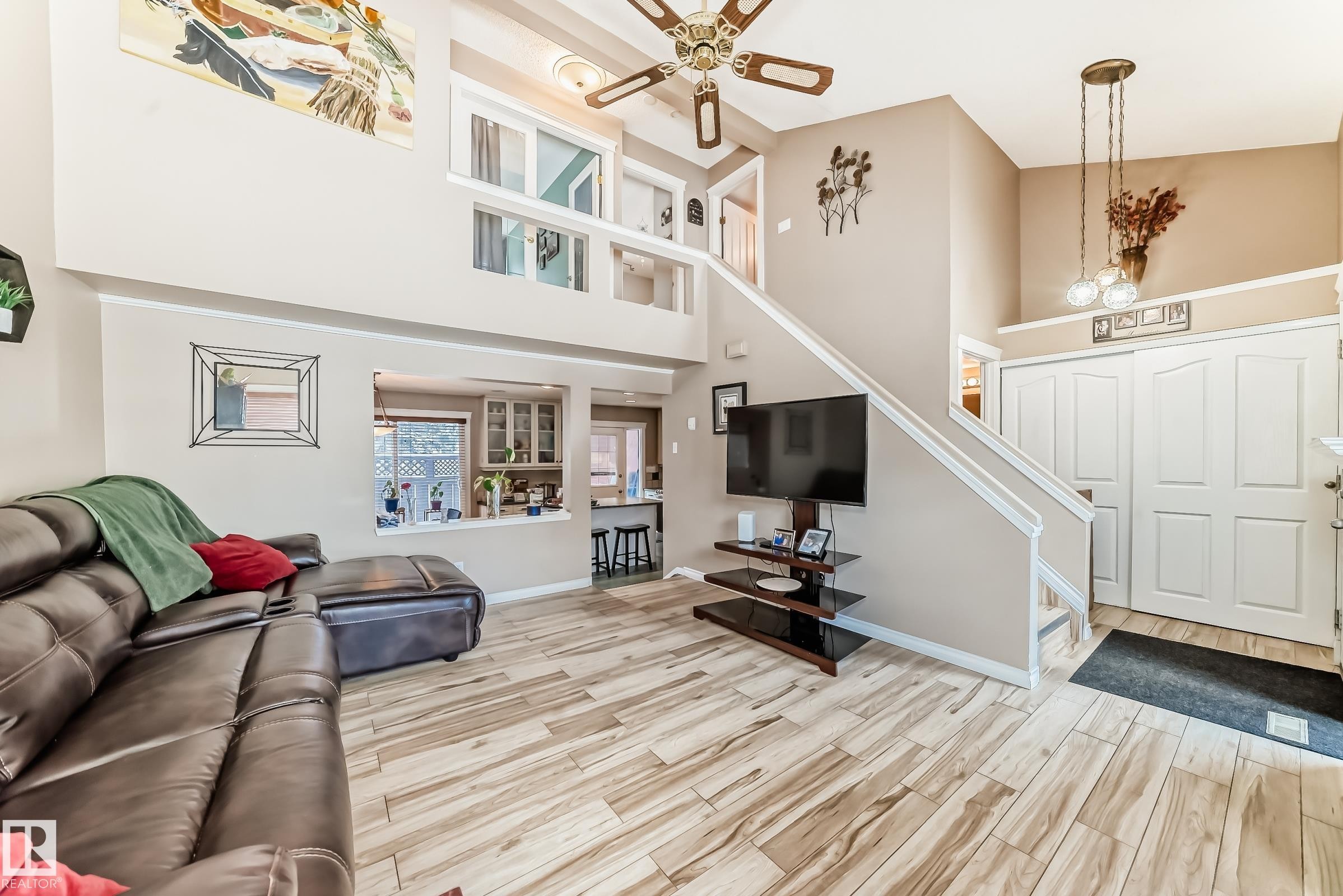 Spacious living area featuring high ceilings, wood-look tile flooring, and a ceiling fan - 597 Millbourne Road E, Edmonton, AB - Indoor
