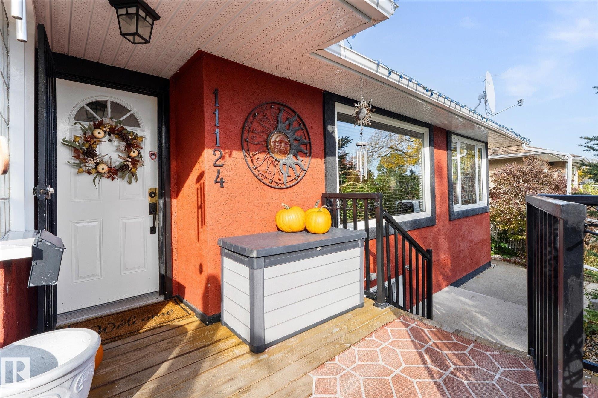 The property features a welcoming front entry with a white door, a red exterior, and a porch with a distinct patterned surface - 11124 110A Avenue, Edmonton, AB - Outdoor With Deck Patio Veranda With Exterior
