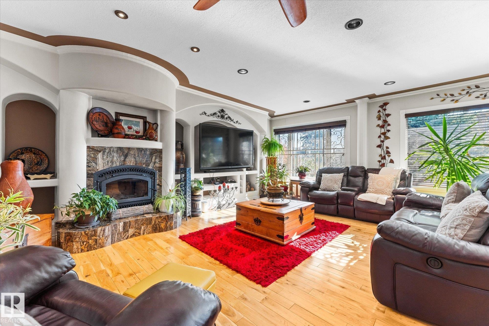 Living room featuring hardwood floors, a stone fireplace, arched alcoves, and recessed lighting - 11124 110A Avenue, Edmonton, AB - Indoor Photo Showing Living Room With Fireplace