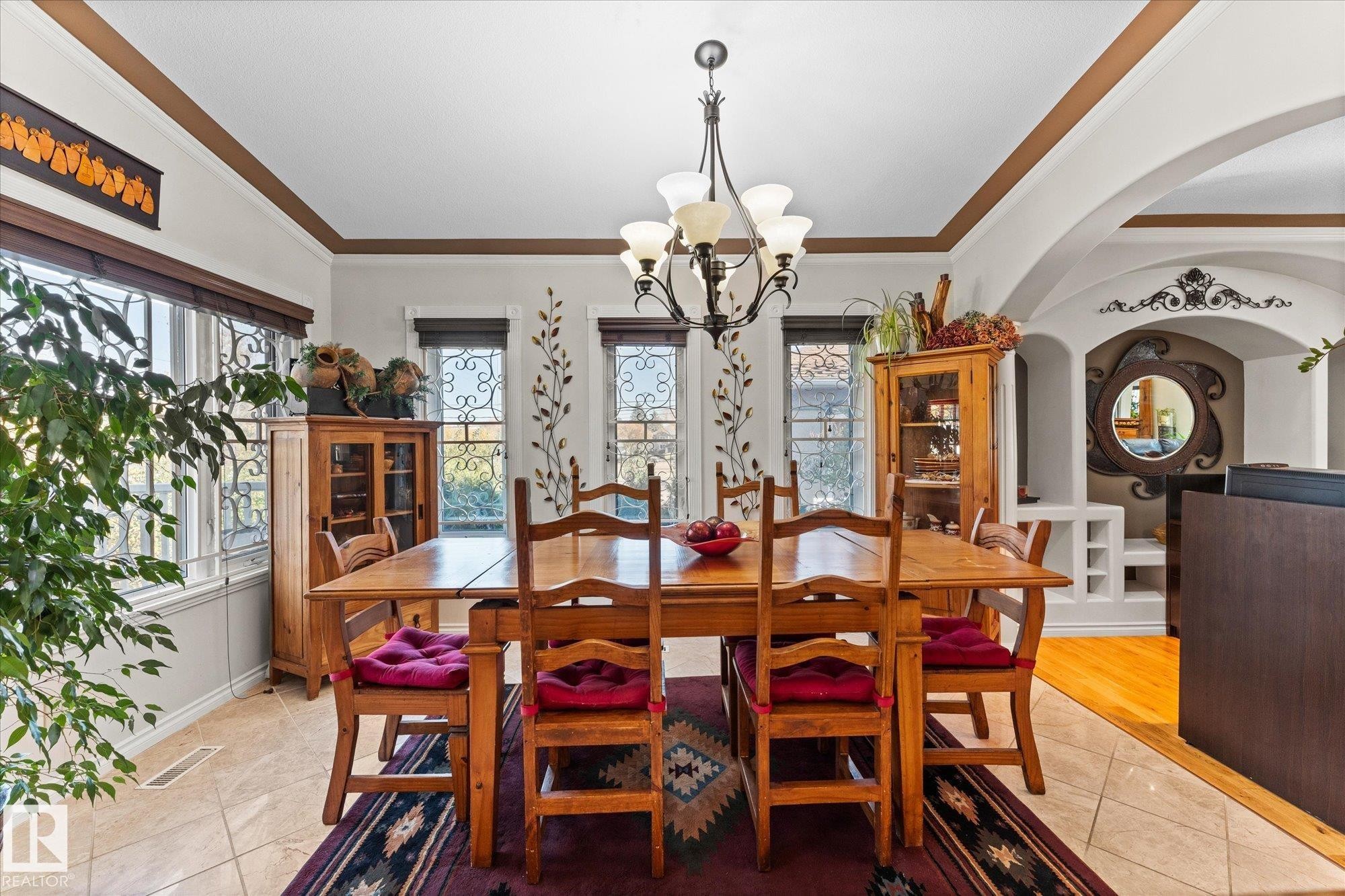 The dining area features a chandelier, tiled flooring, and multiple windows with decorative ironwork - 11124 110A Avenue, Edmonton, AB - Indoor Photo Showing Dining Room