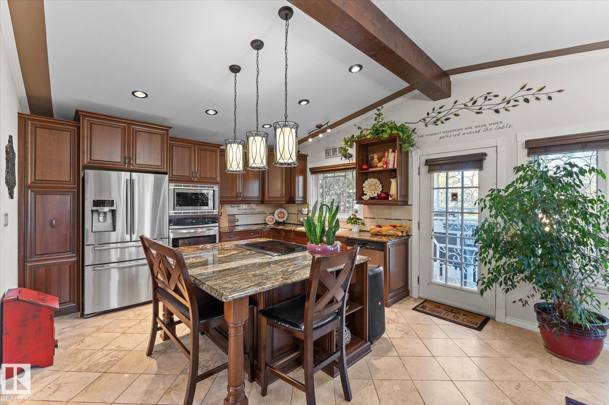 The kitchen features extensive wood cabinetry, stainless steel appliances, a large island with a granite countertop, and recessed lighting - 11124 110A Avenue, Edmonton, AB - Indoor