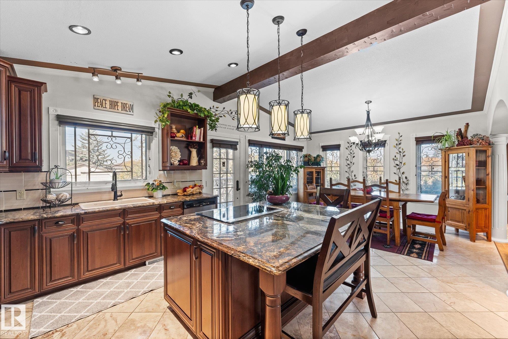 The property features a kitchen with dark wood cabinetry, granite countertops, and a center island with a cooktop - 11124 110A Avenue, Edmonton, AB - Indoor Photo Showing Other Room