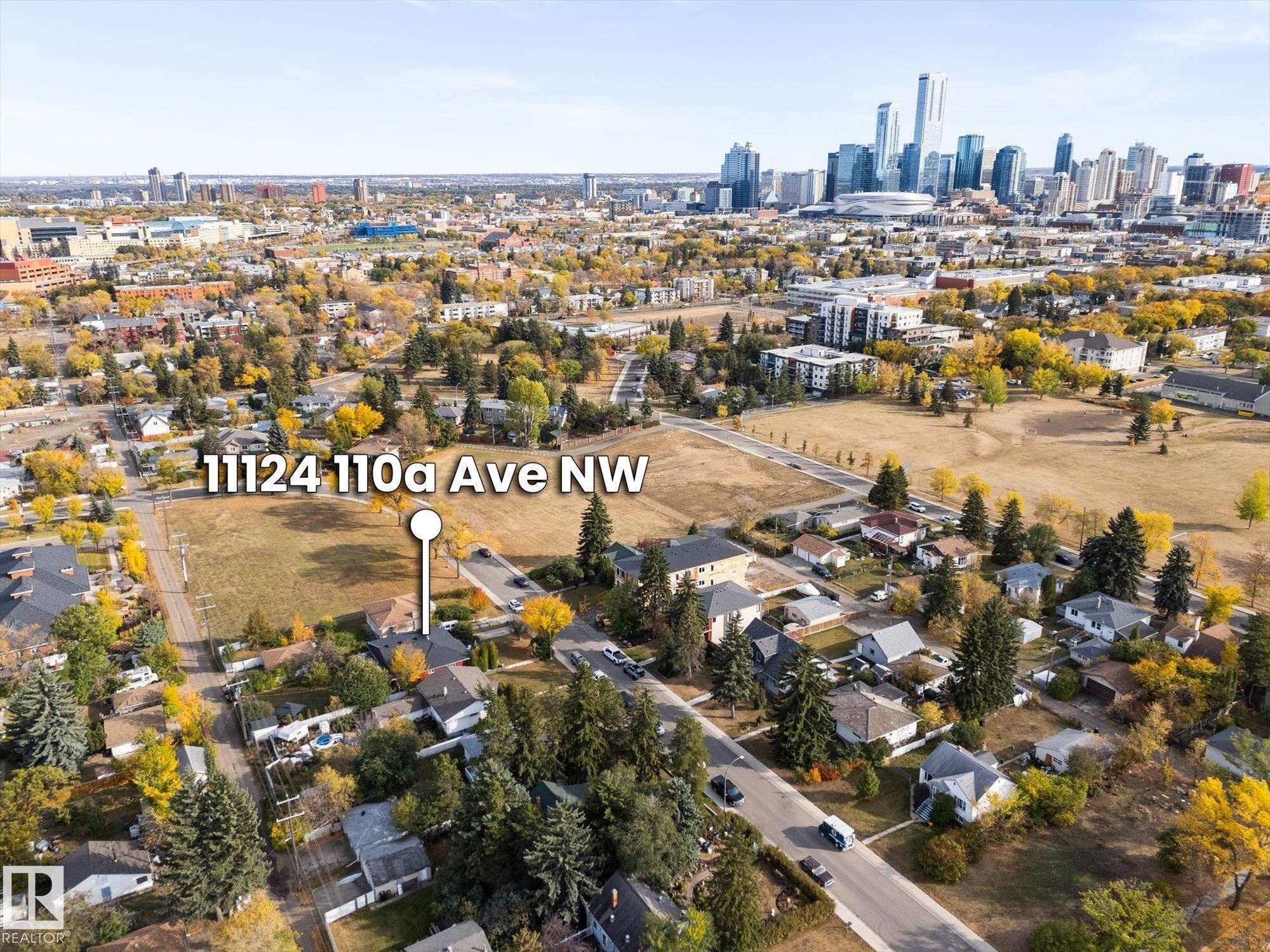 The property is situated in a neighborhood with extensive greenery, featuring mature trees and open grassy areas, and offers views of the city skyline - 11124 110A Avenue, Edmonton, AB - Outdoor With View