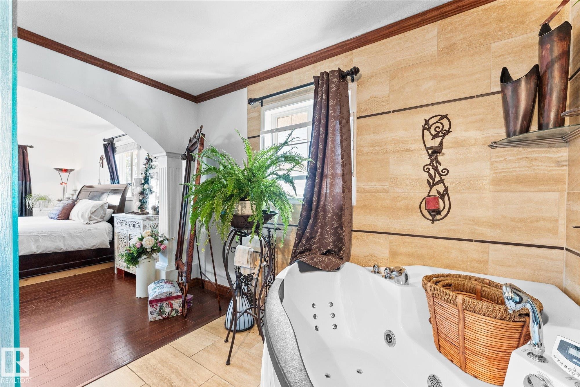 The primary bathroom features a white soaking tub with jets, and a window with brown drapes - 11124 110A Avenue, Edmonton, AB - Indoor