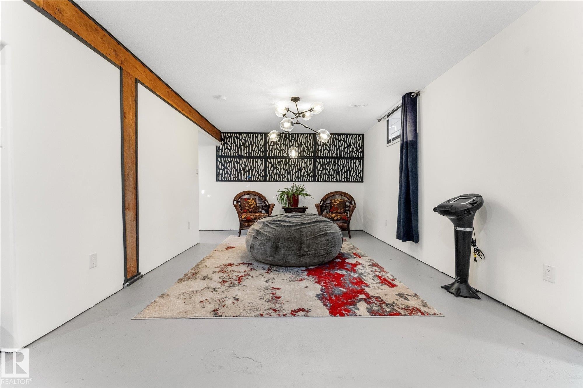 The property features a spacious room with white walls, exposed wooden beams, and a window with a dark curtain - 11124 110A Avenue, Edmonton, AB - Indoor