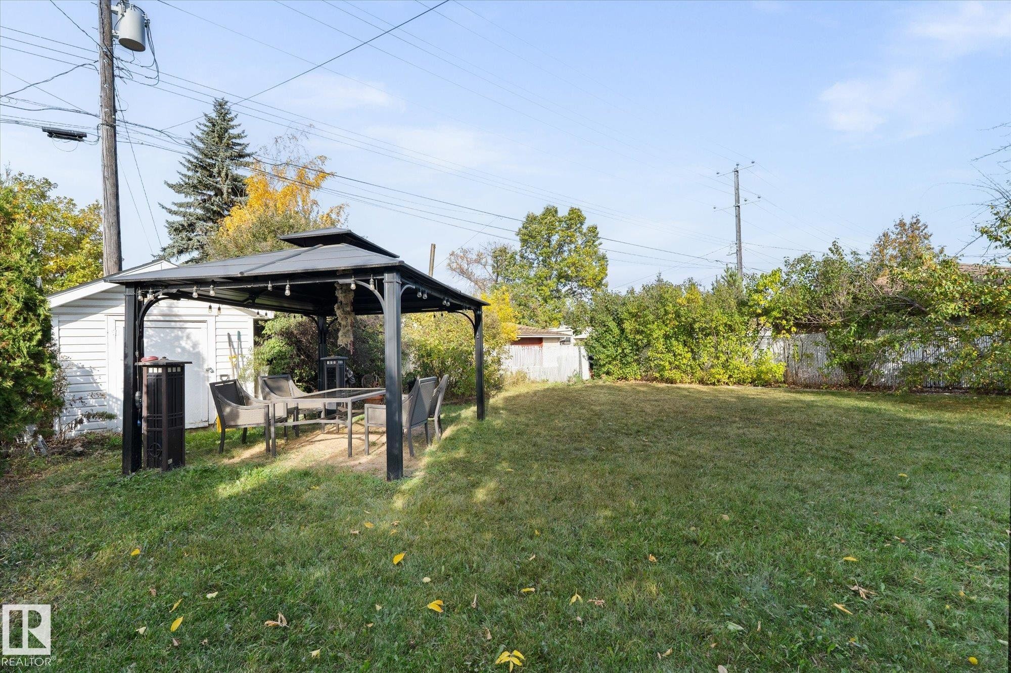 The property features a spacious lawn area, a gazebo, and a detached white shed - 11124 110A Avenue, Edmonton, AB - Outdoor