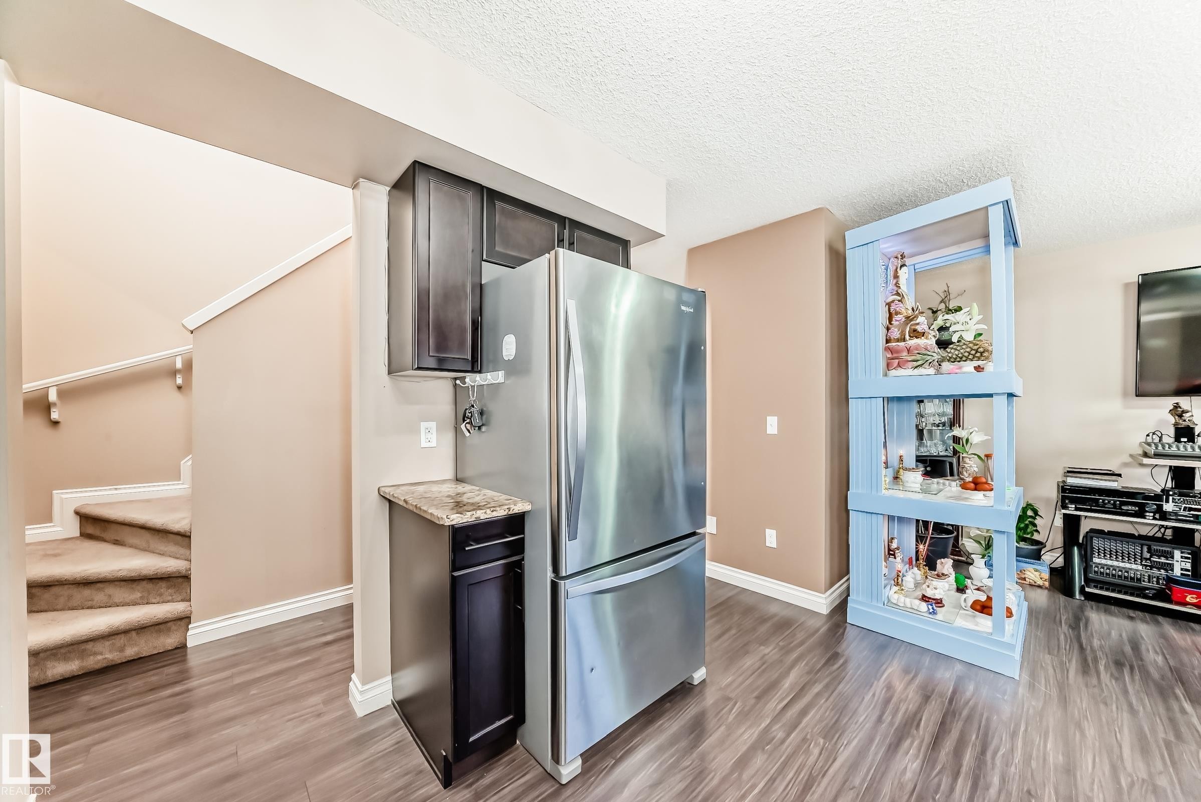 Kitchen area featuring stainless steel appliances, dark wood cabinetry, and a countertop with a polished finish - 23 445 Brintnell Boulevard Nw, Edmonton, AB - Indoor