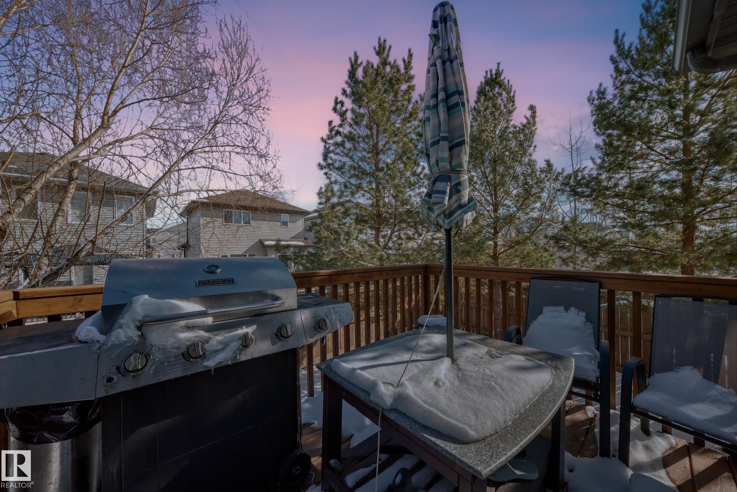 Expansive wood deck with a wooden railing and a view of trees - 23 445 Brintnell Boulevard Nw, Edmonton, AB - Outdoor