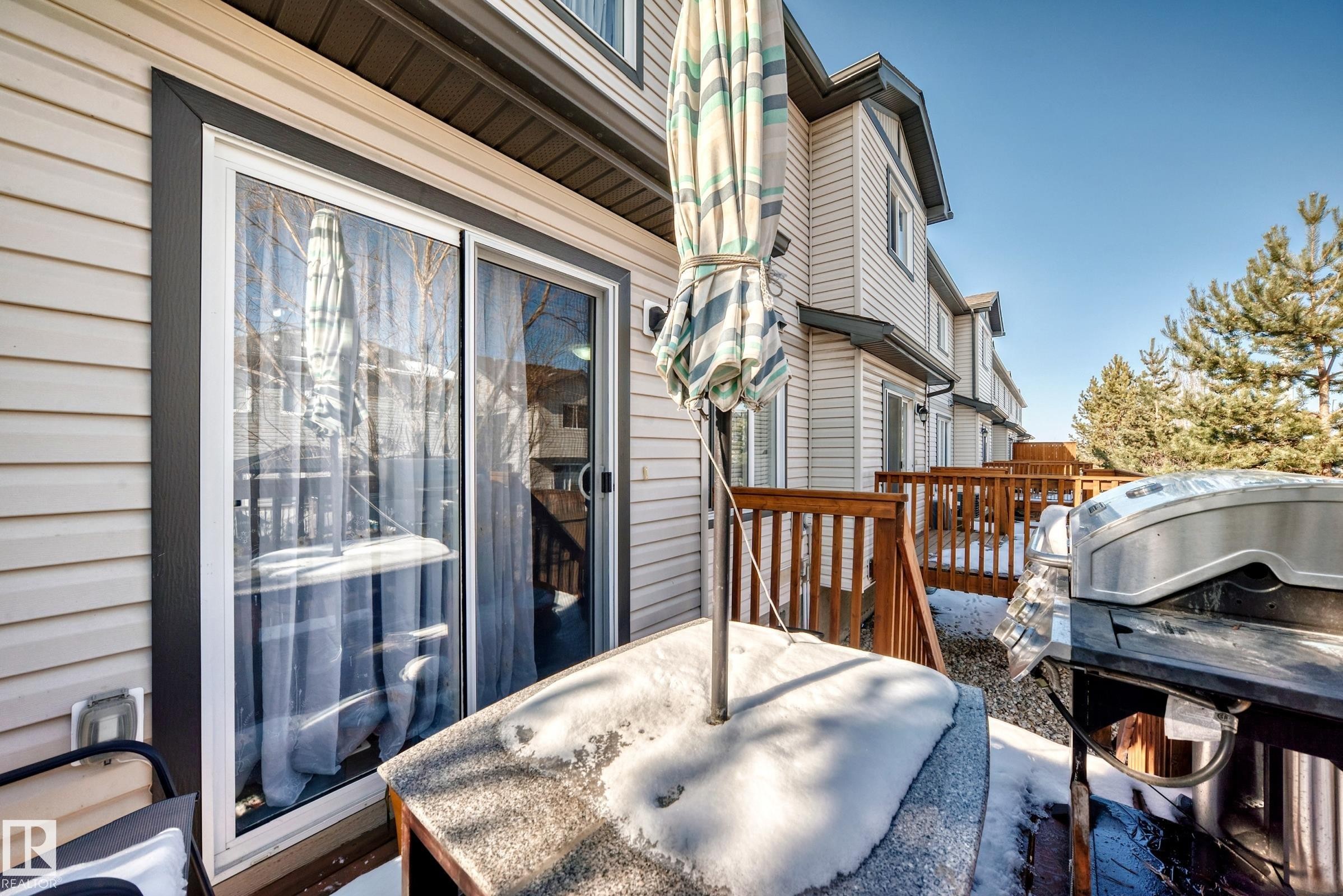 The property features a private deck with wooden railings and a sliding glass door - 23 445 Brintnell Boulevard Nw, Edmonton, AB - Outdoor With Deck Patio Veranda With Exterior