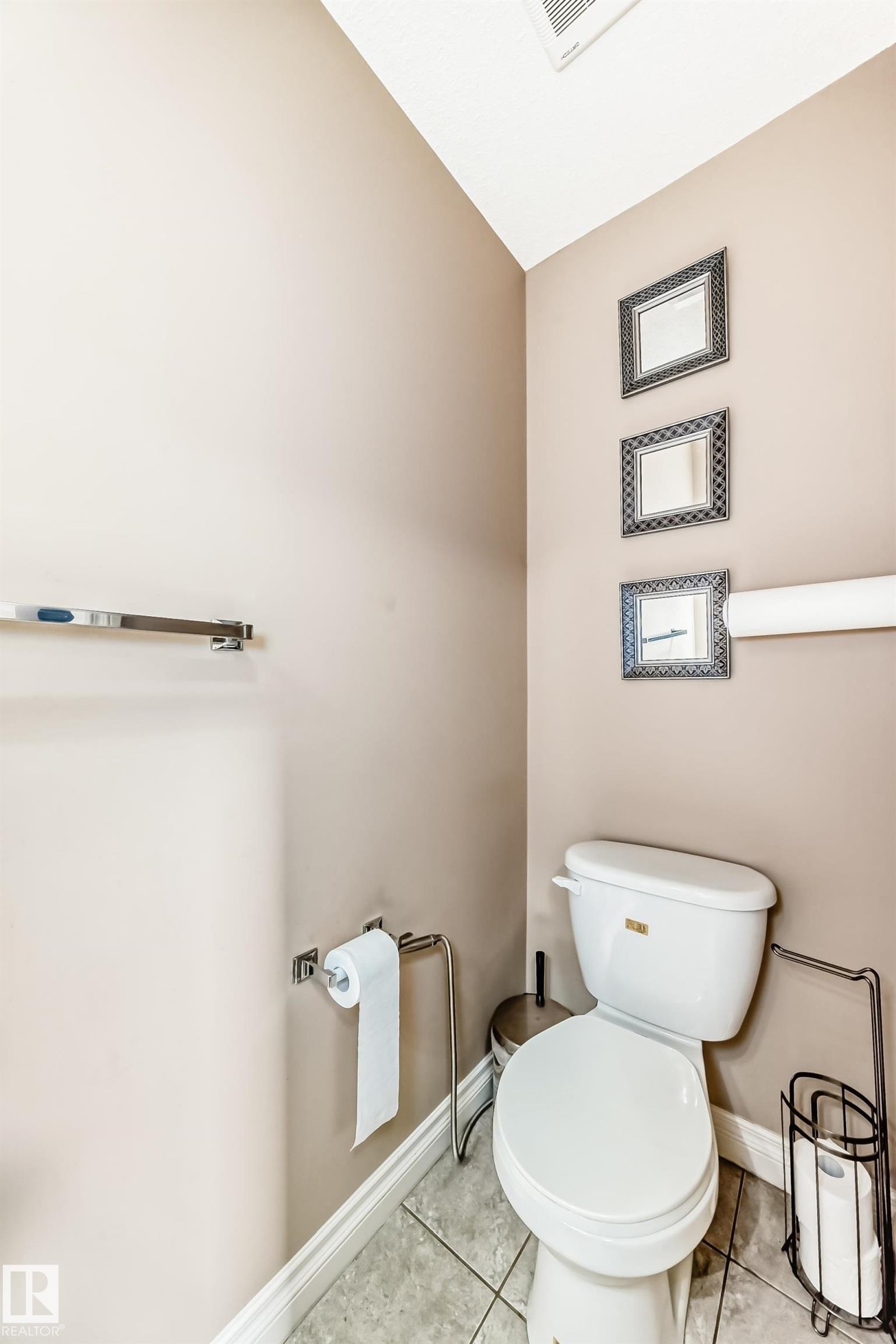 This powder room features neutral-toned walls, a white toilet, and tiled flooring - 23 445 Brintnell Boulevard Nw, Edmonton, AB - Indoor Photo Showing Bathroom