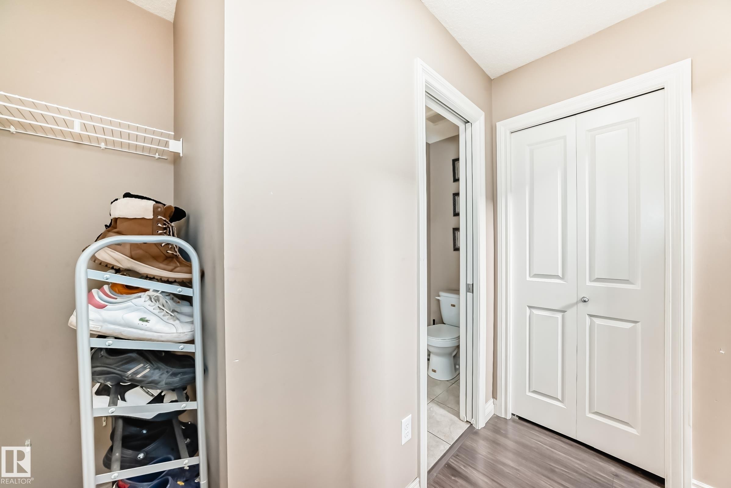 The property features a closet with a white wire shelf, a white bi-fold door, and wood-look flooring - 23 445 Brintnell Boulevard Nw, Edmonton, AB - Indoor Photo Showing Other Room