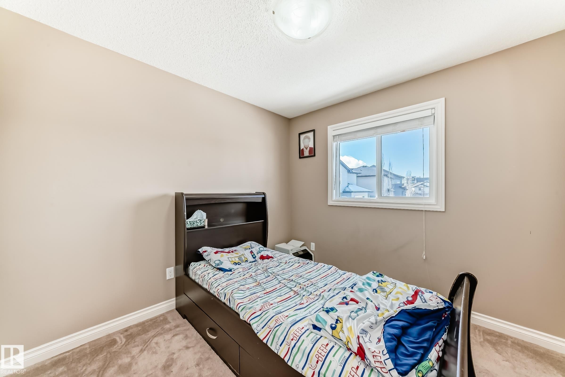 This room features a window providing natural light, a neutral-toned carpet, and a light-colored wall paint - 23 445 Brintnell Boulevard Nw, Edmonton, AB - Indoor Photo Showing Bedroom