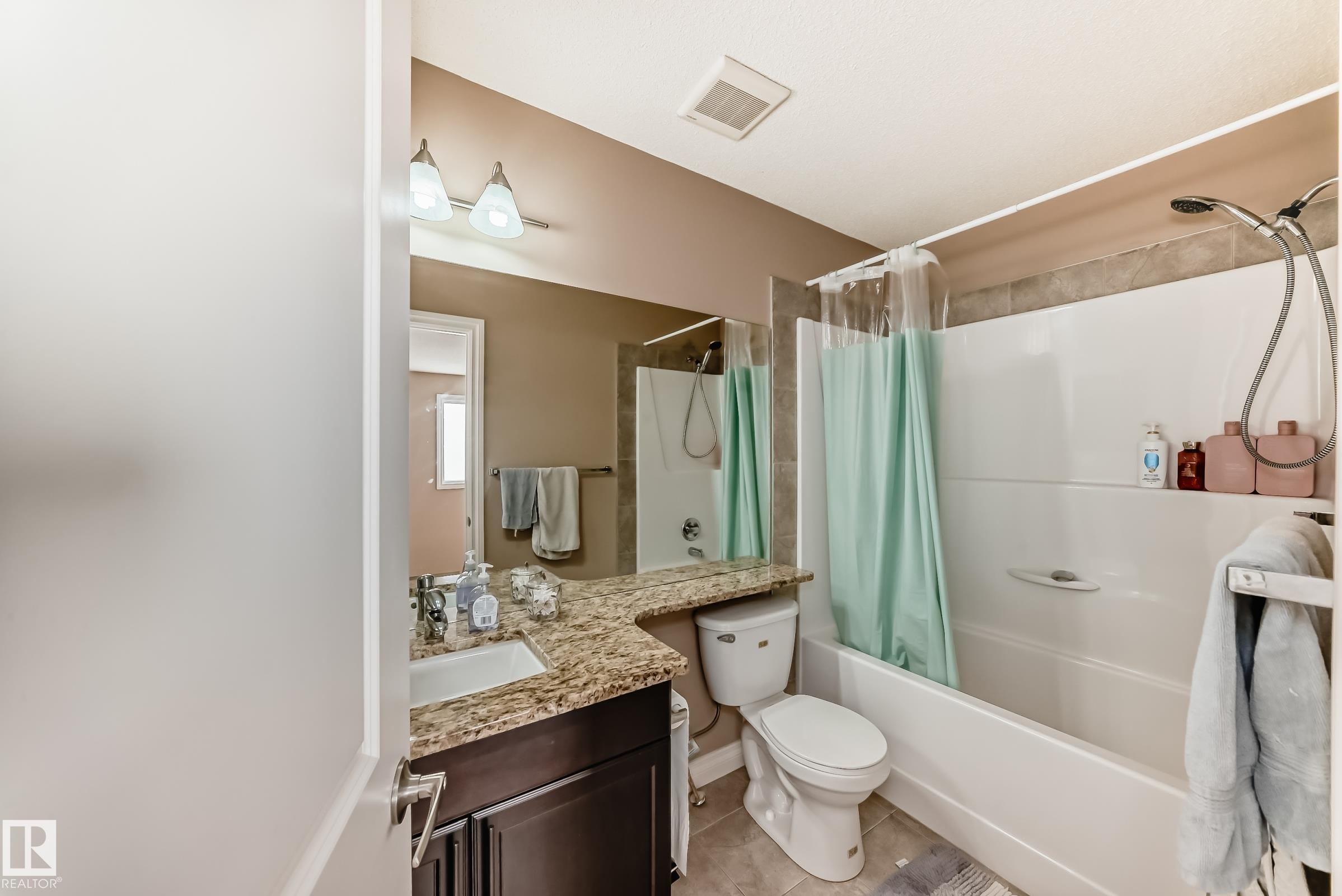 The bathroom features a vanity with a granite countertop and a white sink, an overhead light fixture, and a bathtub with a shower - 23 445 Brintnell Boulevard Nw, Edmonton, AB - Indoor Photo Showing Bathroom
