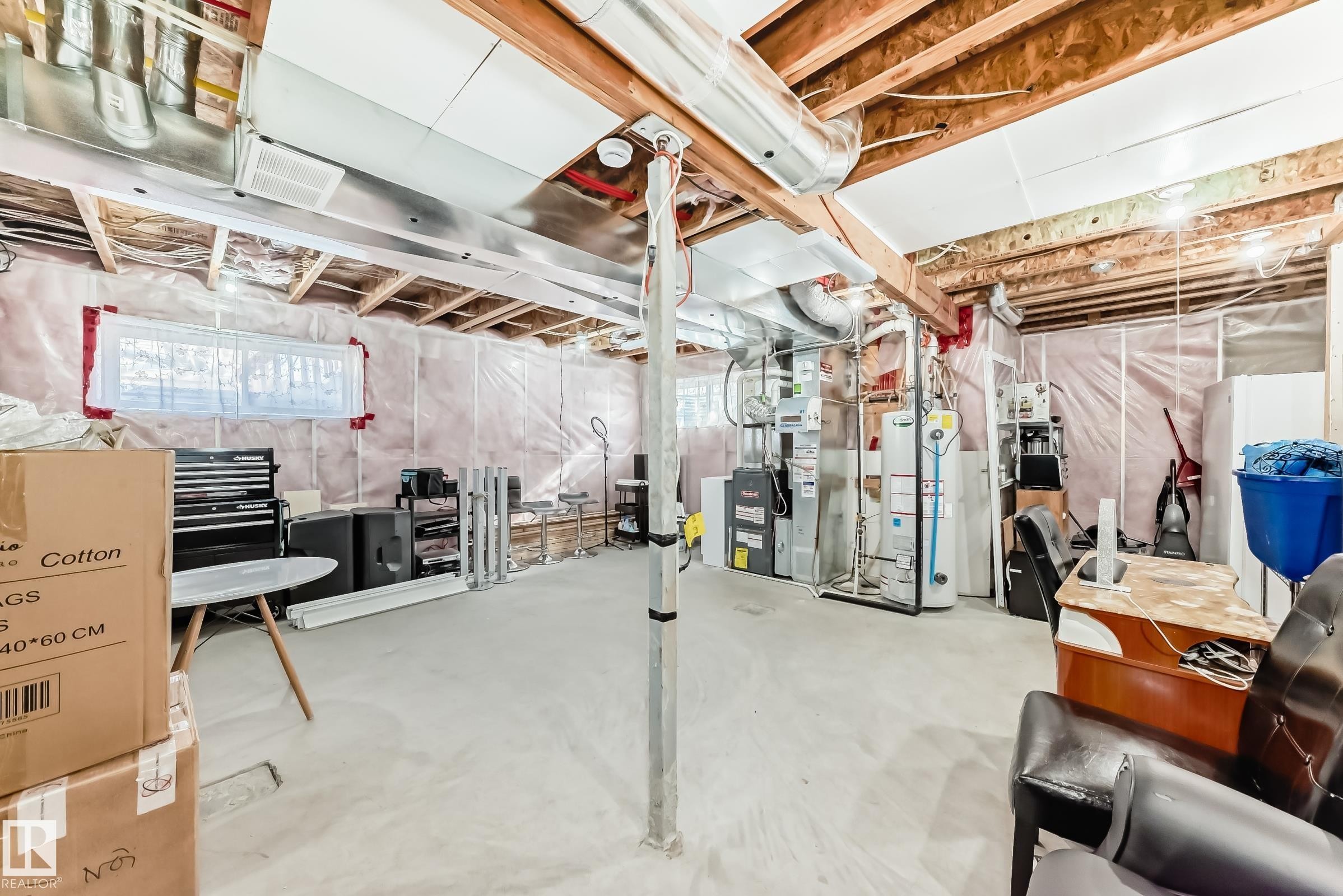 The unfinished basement offers an expansive open area, exposed ceiling beams, and a window providing natural light - 23 445 Brintnell Boulevard Nw, Edmonton, AB - Indoor Photo Showing Basement