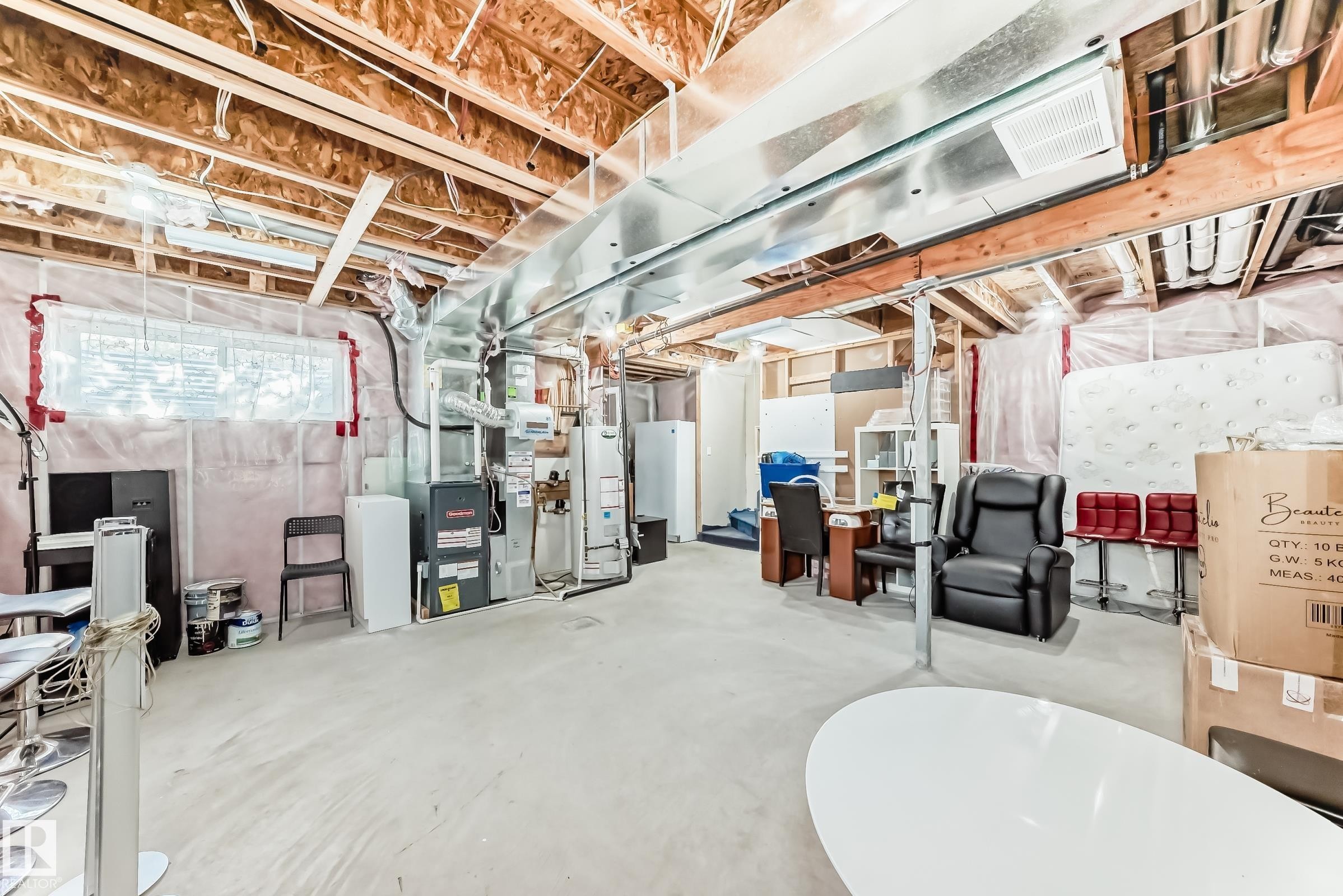 The unfinished basement offers an expansive open area with visible structural elements and utilities, including exposed ceiling joists, ductwork, and a furnace - 23 445 Brintnell Boulevard Nw, Edmonton, AB - Indoor Photo Showing Basement