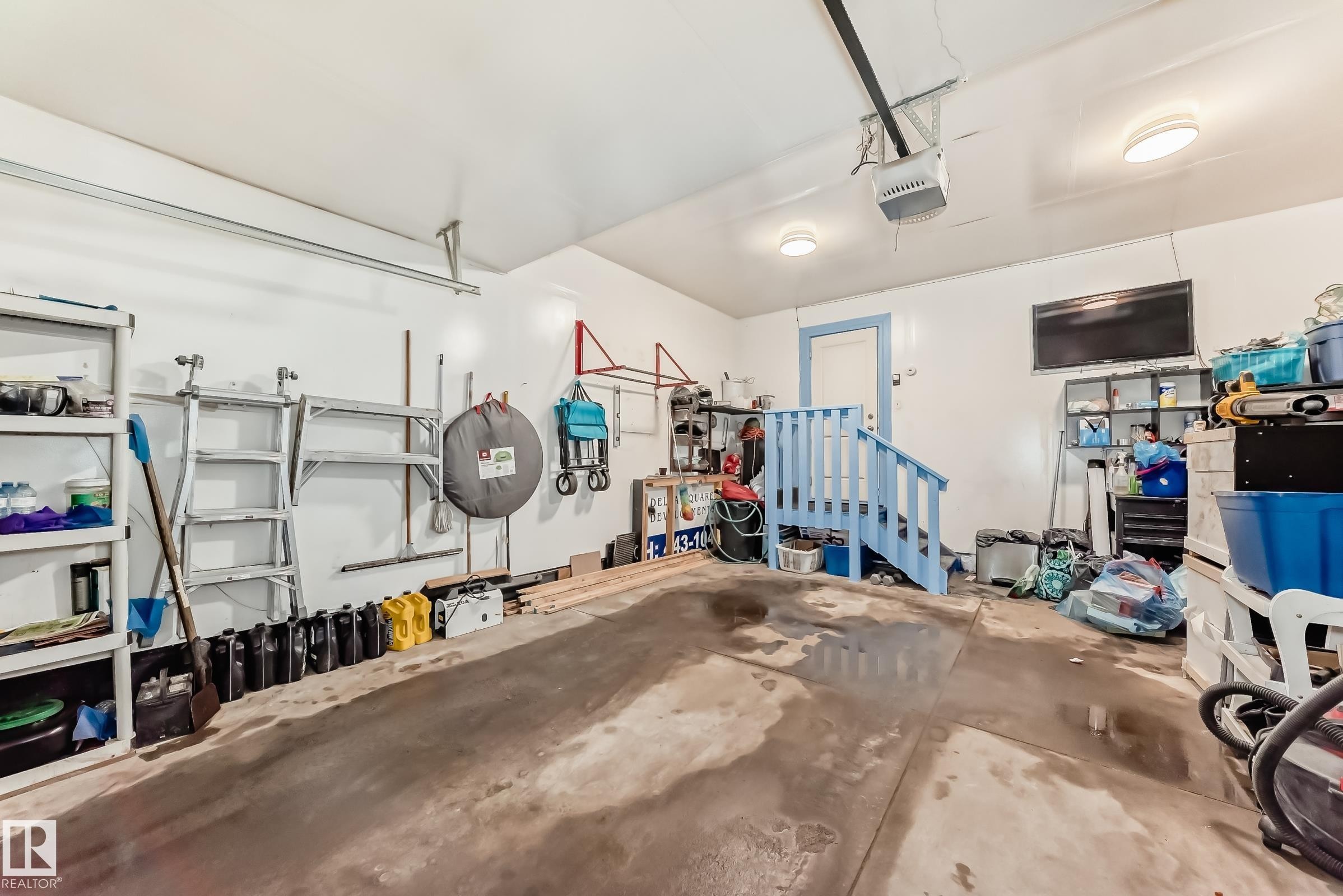 The property includes a garage featuring a concrete floor, white walls, and overhead lighting - 23 445 Brintnell Boulevard Nw, Edmonton, AB - Indoor Photo Showing Garage