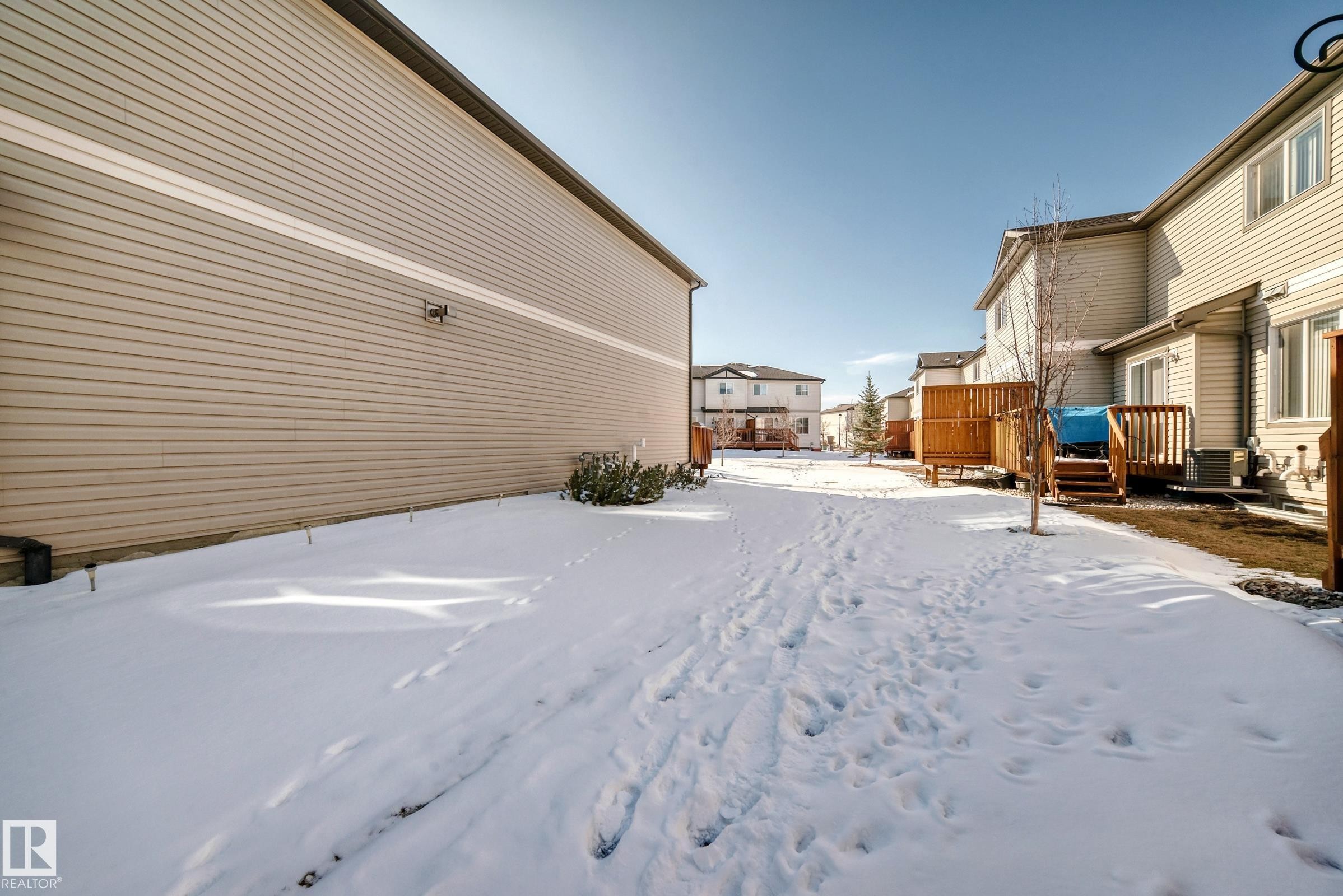 The property features a private yard with a wooden deck and privacy screen, offering outdoor living space - 23 445 Brintnell Boulevard Nw, Edmonton, AB - Outdoor With Exterior