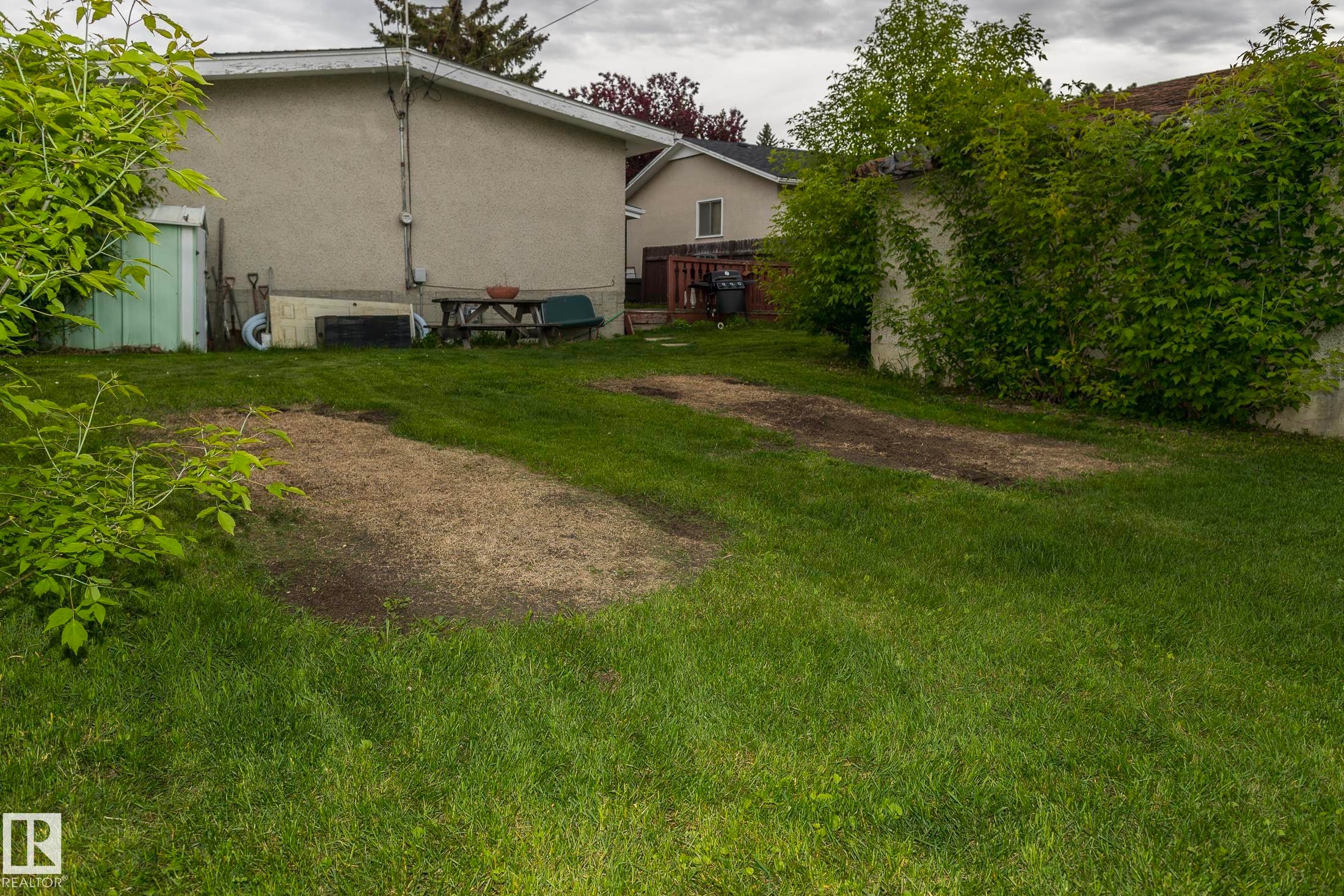 The property features a spacious lawn with established greenery and a stucco exterior - 10512 55 Avenue, Edmonton, AB - Outdoor