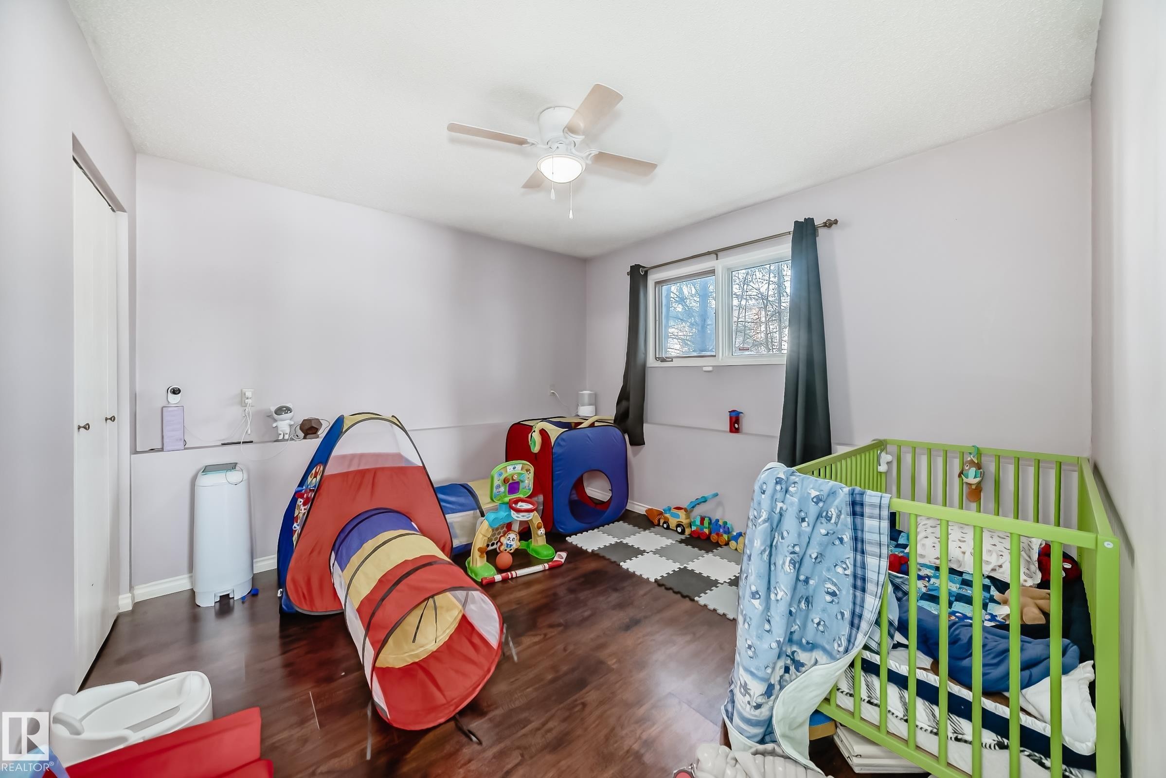 This room features hardwood flooring, light purple walls, and a window with dark curtains - 16232 100 Street, Edmonton, AB - Indoor