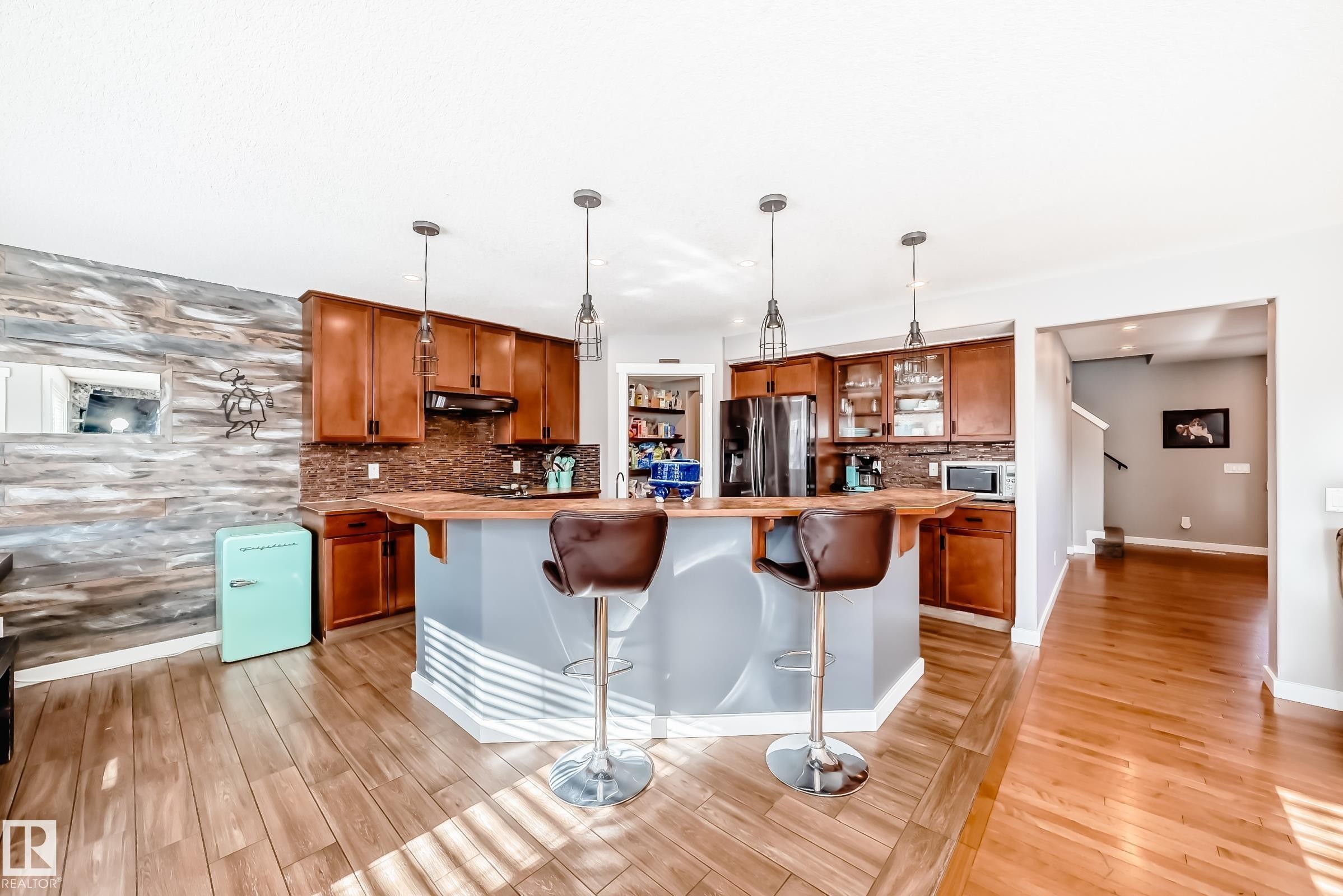 The kitchen features wood cabinetry, a tiled backsplash, and an island with seating for two - 6303 2 Avenue, Edmonton, AB - Indoor Photo Showing Kitchen With Upgraded Kitchen