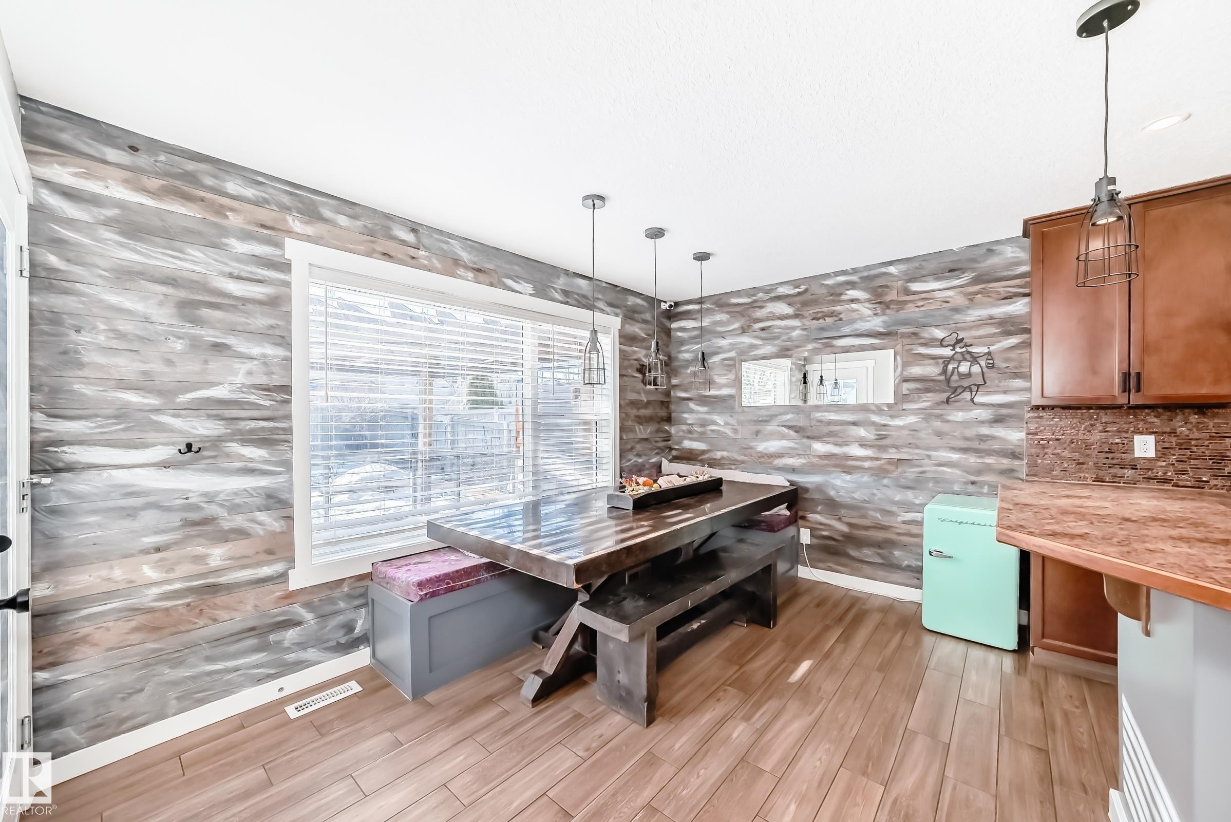 This dining area features wood-look flooring, a window with blinds, and unique wall paneling - 6303 2 Avenue, Edmonton, AB - Indoor Photo Showing Kitchen