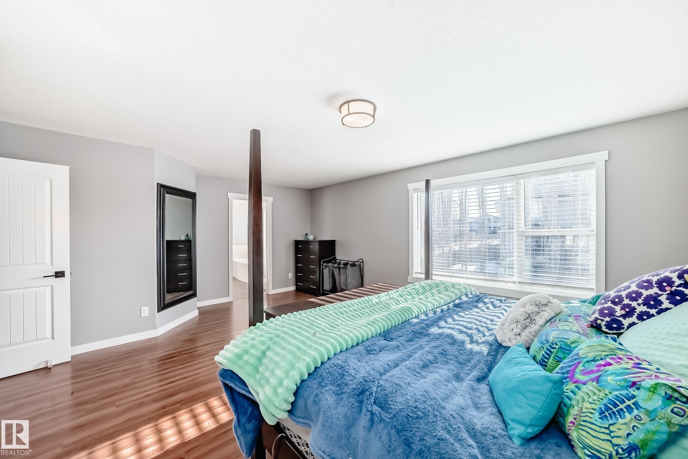This room features hardwood flooring, light grey walls, and a large window with blinds - 6303 2 Avenue, Edmonton, AB - Indoor Photo Showing Bedroom