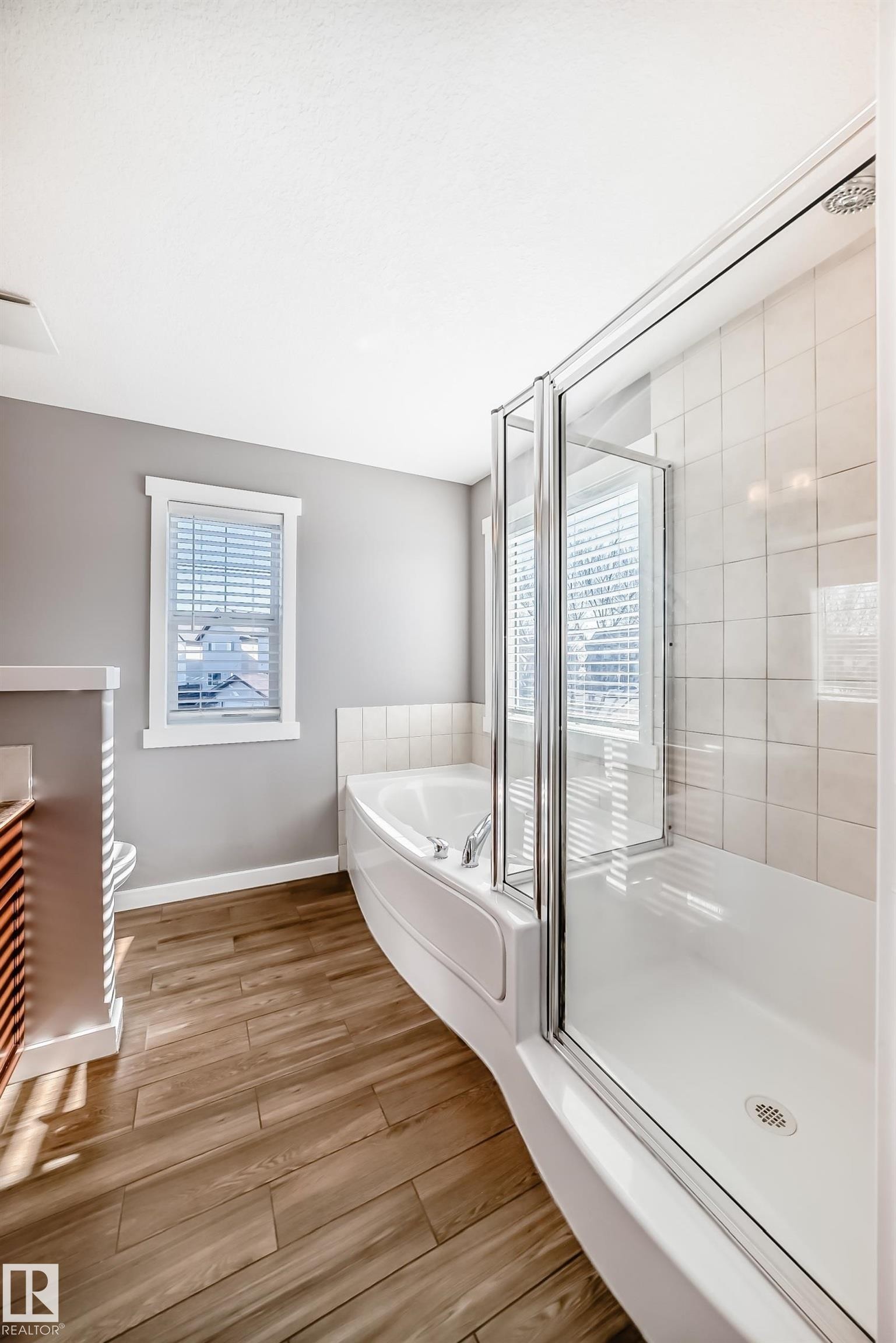 Bathroom featuring a corner bathtub, a glass-enclosed shower, and wood-look flooring - 6303 2 Avenue, Edmonton, AB - Indoor Photo Showing Bathroom