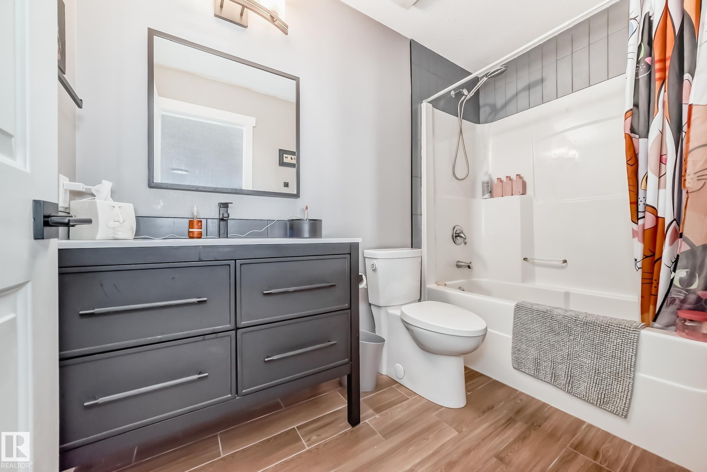 The bathroom features a vanity with a white countertop and a dark cabinet, a mirror, and wood-look flooring - 6303 2 Avenue, Edmonton, AB - Indoor Photo Showing Bathroom