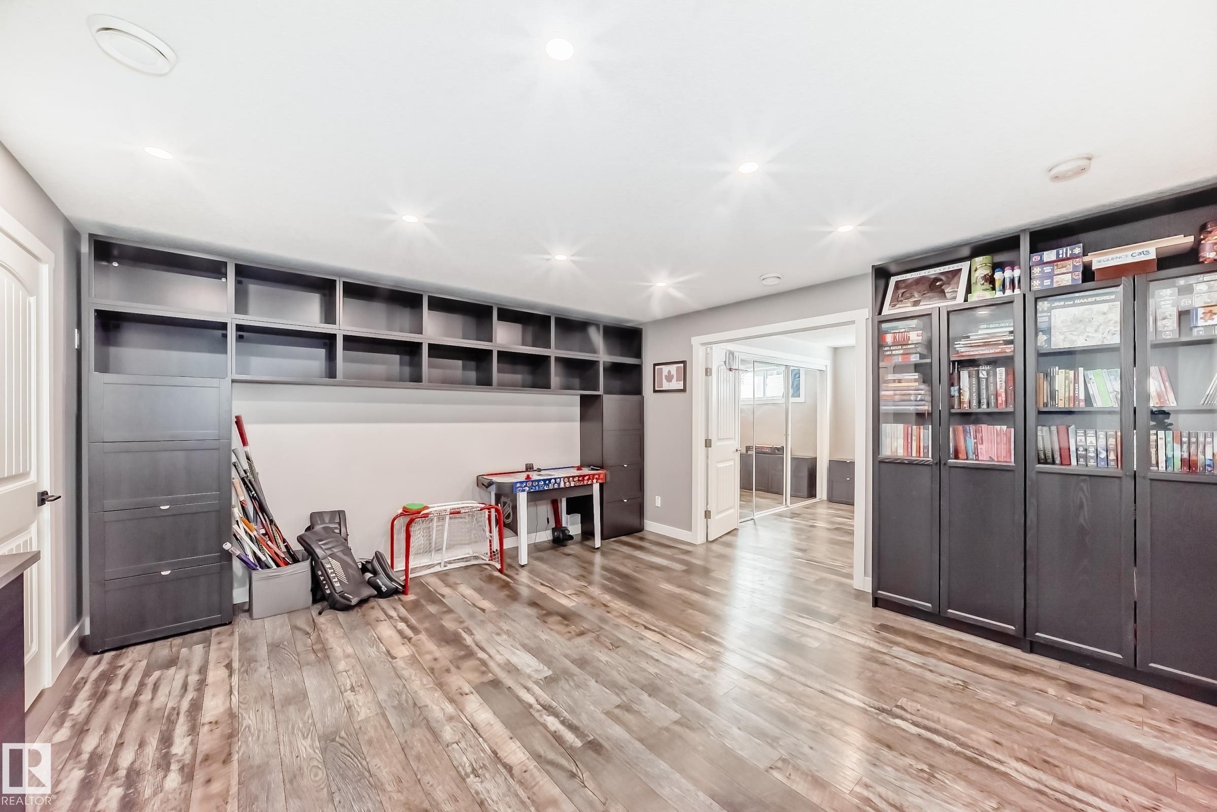 The room features wood-style flooring, recessed lighting, and extensive built-in shelving and cabinetry - 6303 2 Avenue, Edmonton, AB - Indoor