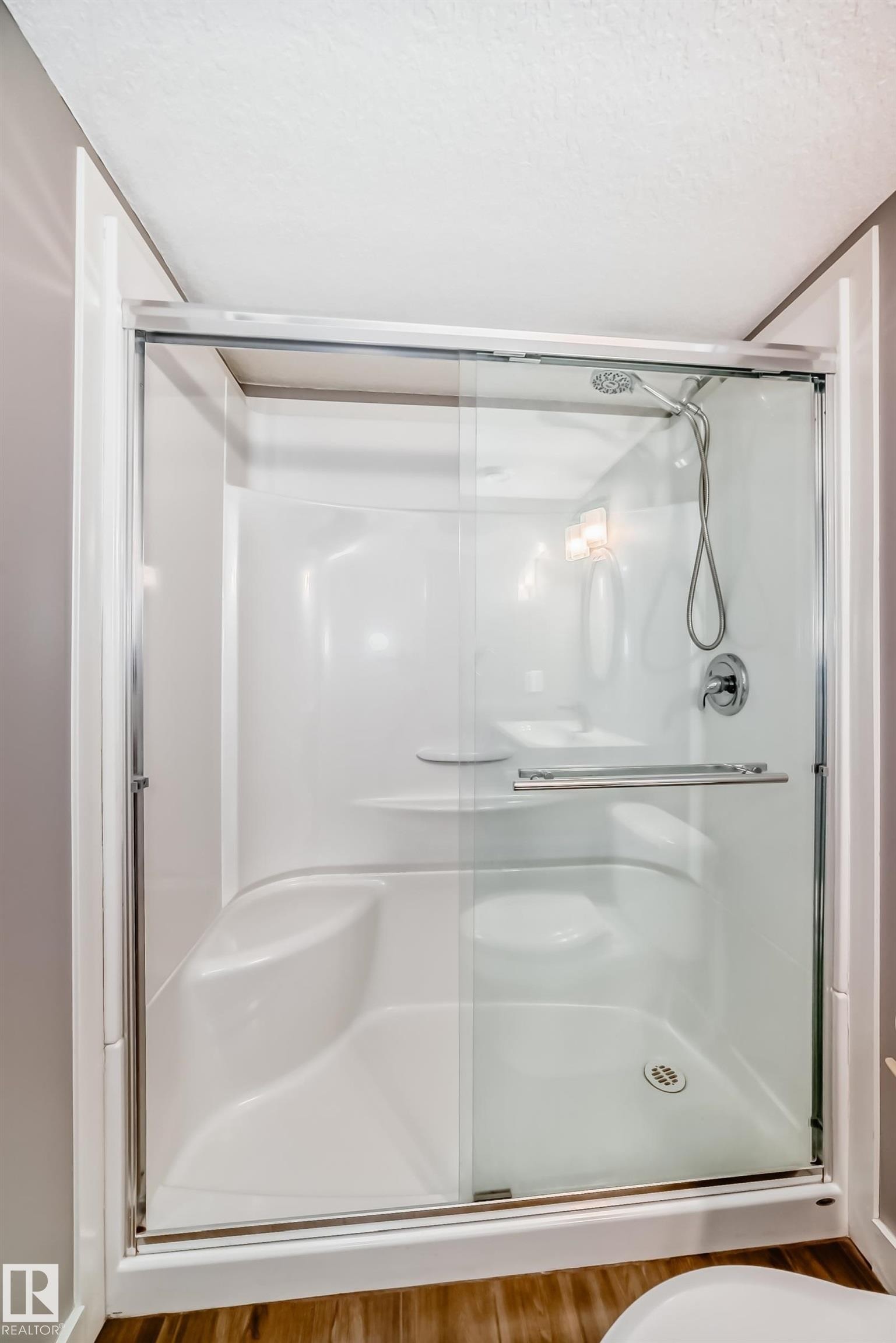 Bathroom featuring a shower with glass sliding doors, a built-in seat, and a shower head with a handheld spray - 6303 2 Avenue, Edmonton, AB - Indoor Photo Showing Bathroom