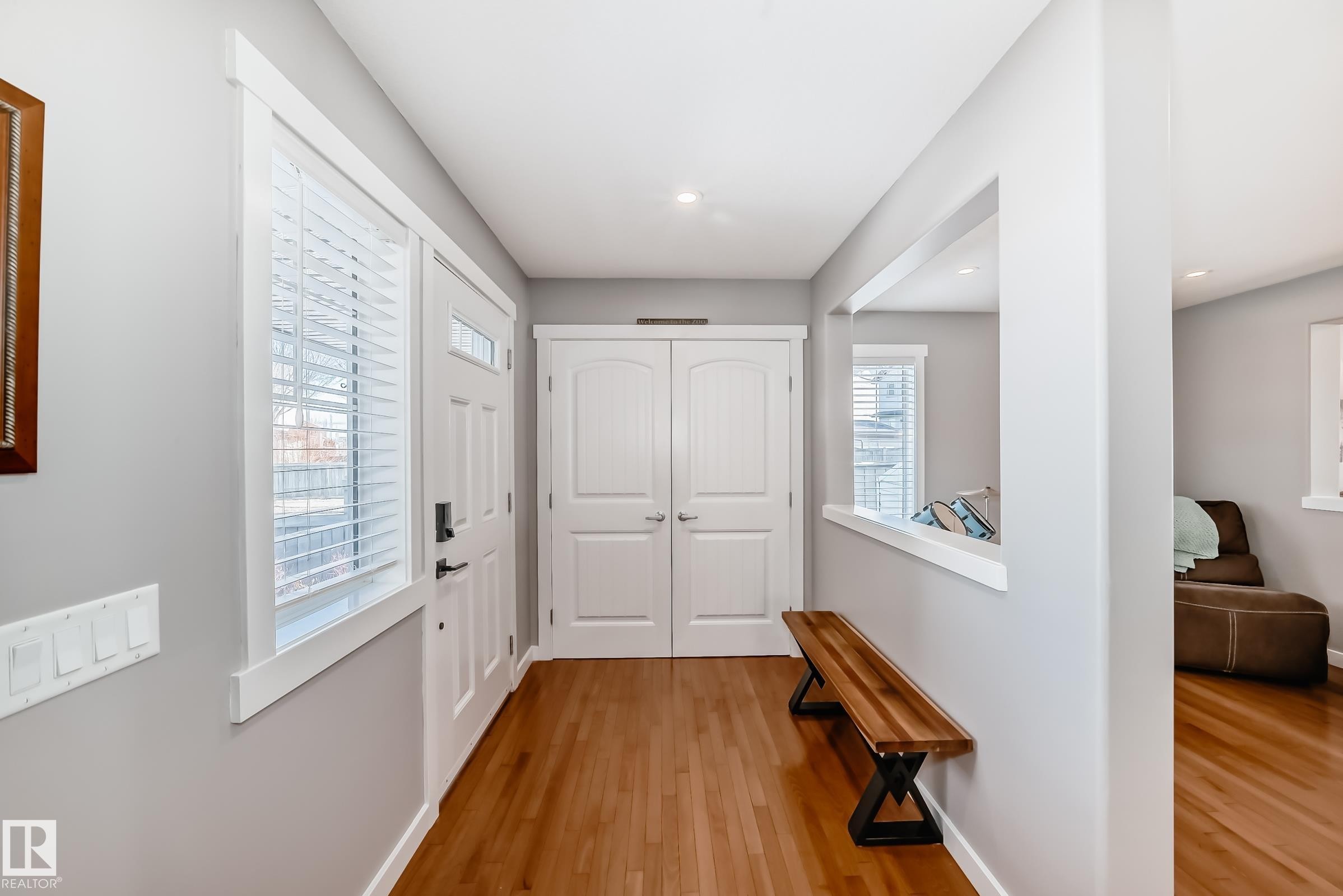 The entryway features hardwood flooring, light grey walls, and a white front door with an adjacent window - 6303 2 Avenue, Edmonton, AB - Indoor Photo Showing Other Room